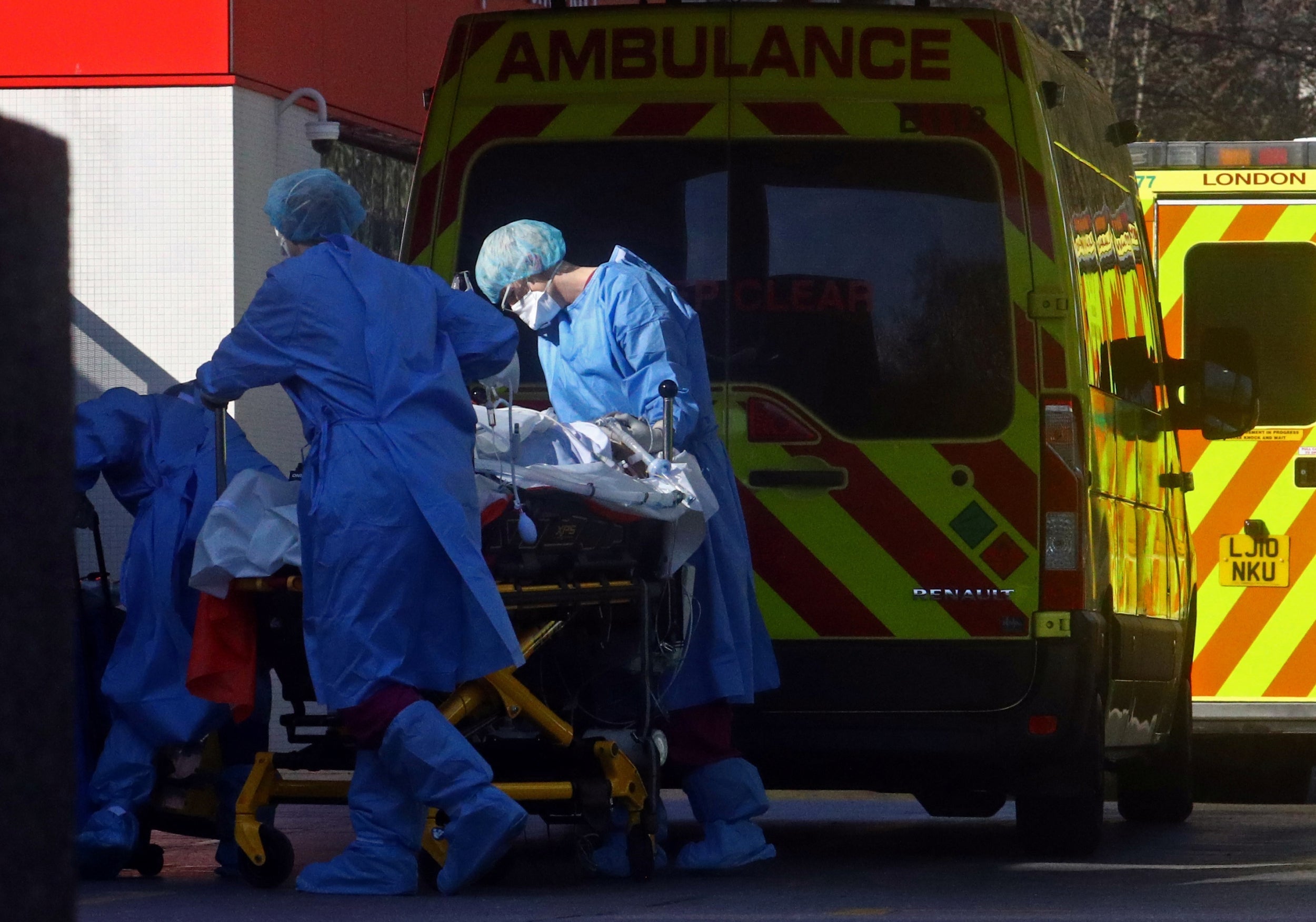 Medical staff with a patient at the back of an ambulance outside a London hospital