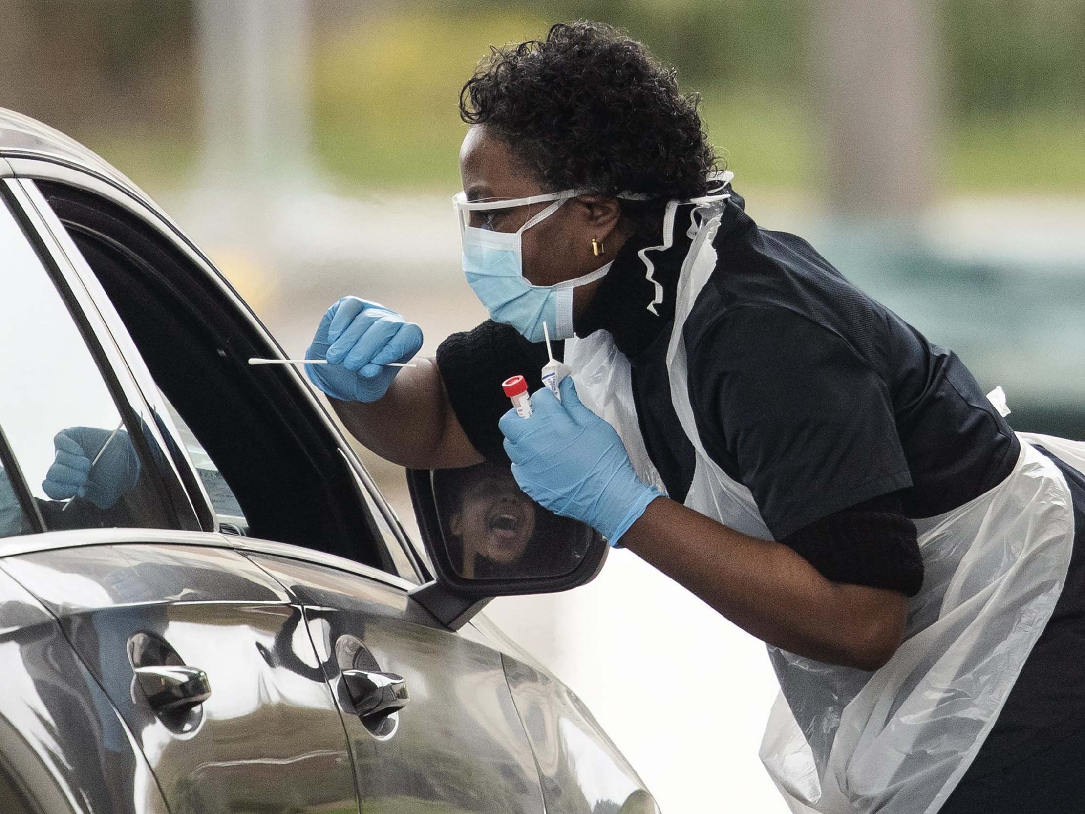 A nurse takes a swab at a drive-through testing station for NHS staff in Chessington