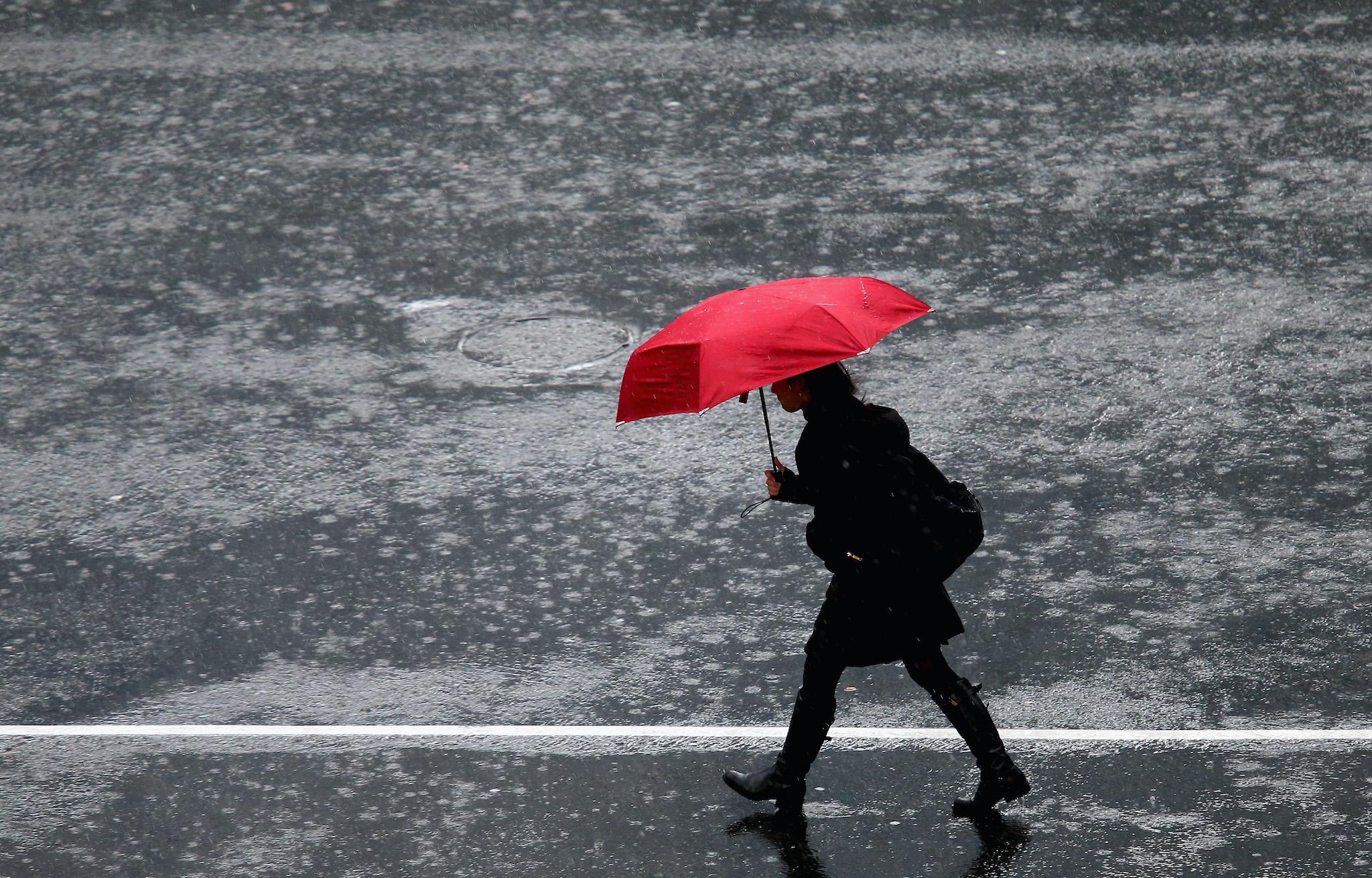 A pedestrian crosses in the intersection of Queen Street and Victoria Street during heavy rain on July 1, 2014 in Auckland, New Zealand