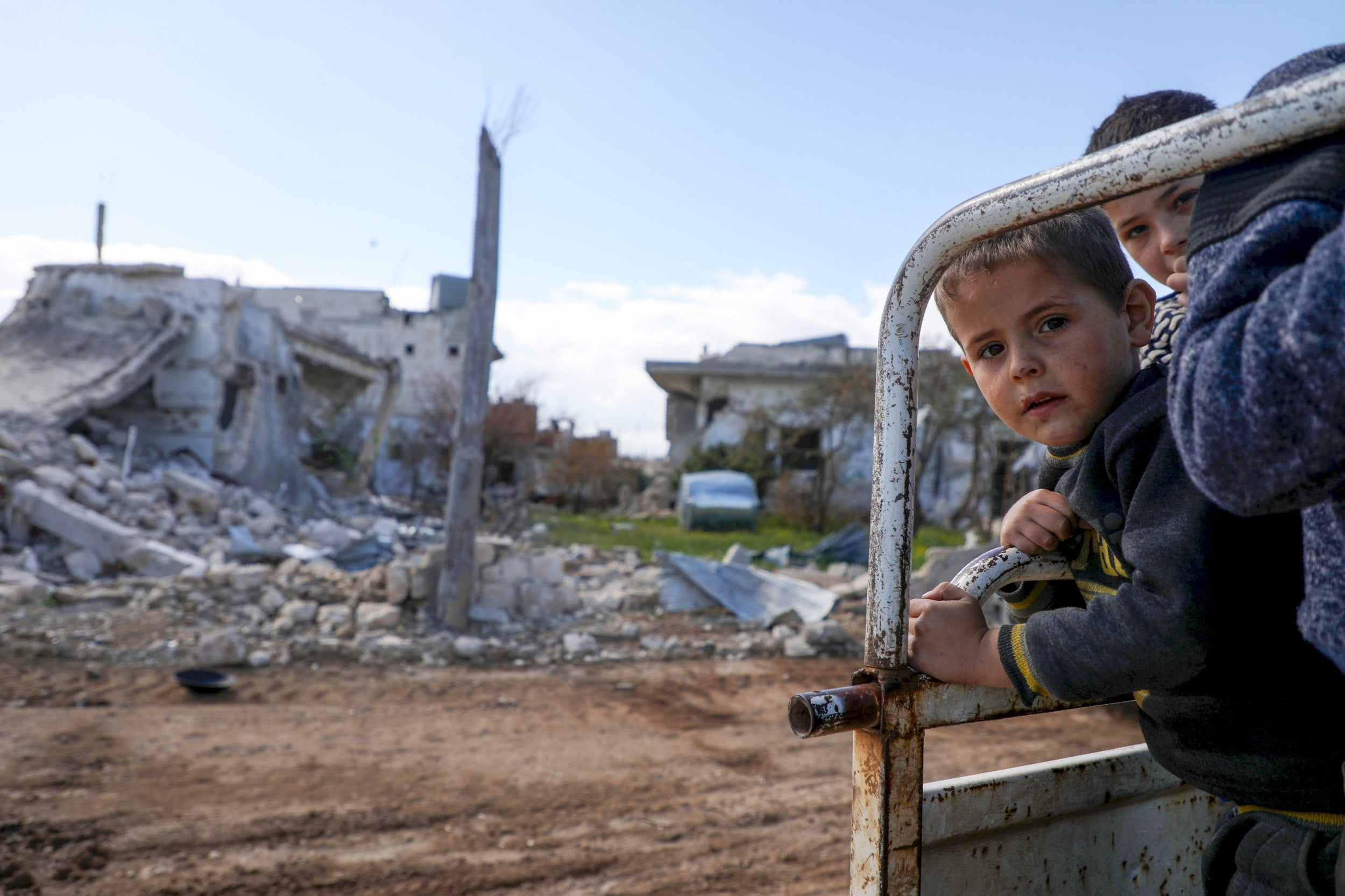 Displaced Syrian boys riding on their family truck as they visit their home in the village of al-Nayrab, northwest Syria