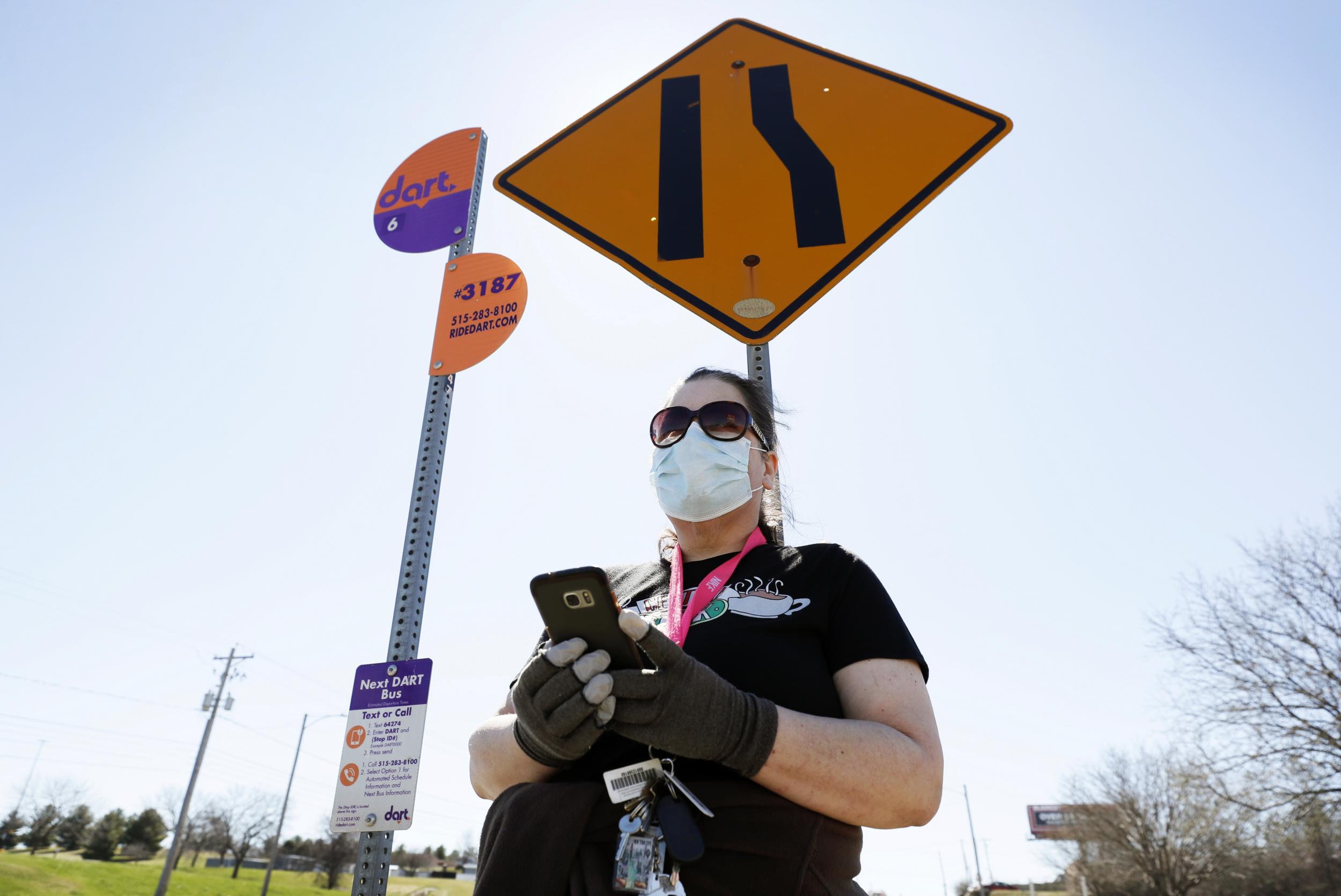 Maryam Jorgensen of Des Moines, Iowa waits for a bus to the grocery store. The state is among a handful without any stay-at-home measures.