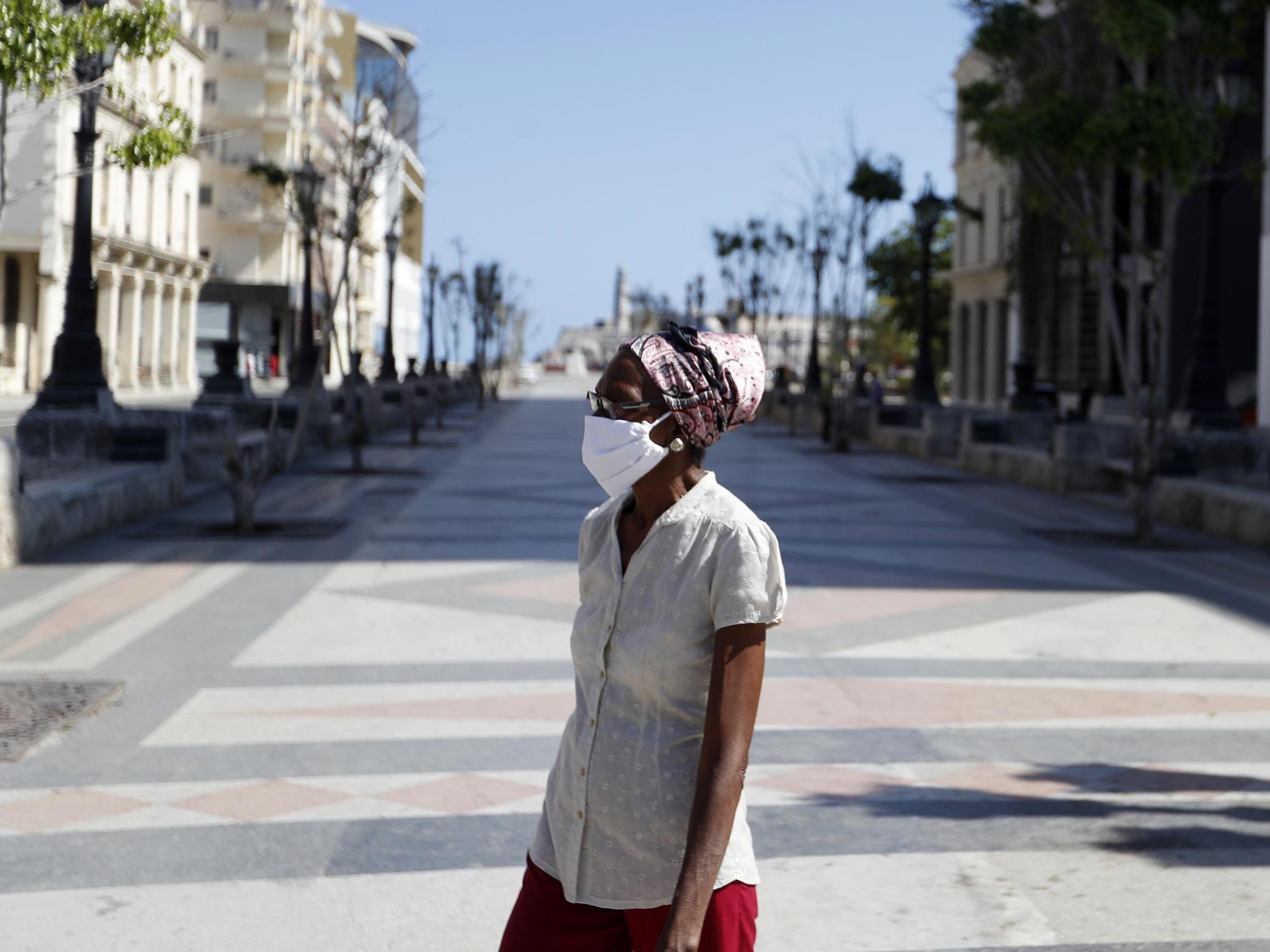 A woman wearing face mask walks along empty Paseo del Prado as protective measures against coronavirus (Covid-19) pandemic are taken in Havana, Cuba