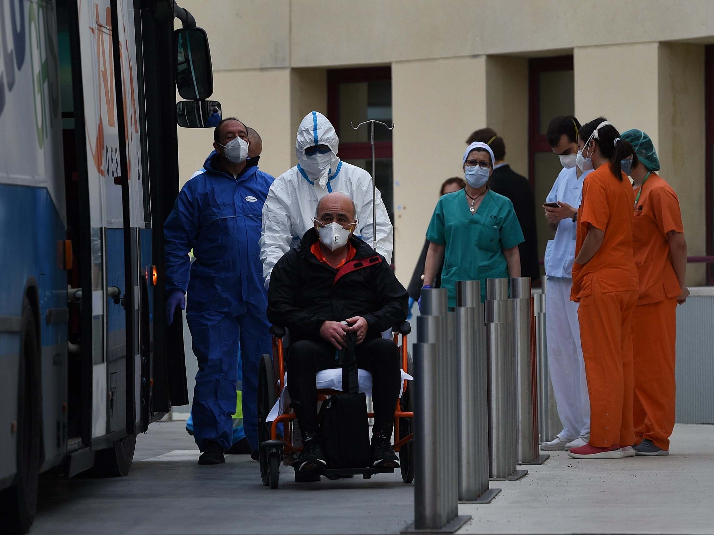 A patient is taken from Gregorio Marinon hospital onto a waiting bus to go to the IFEMA field hospital