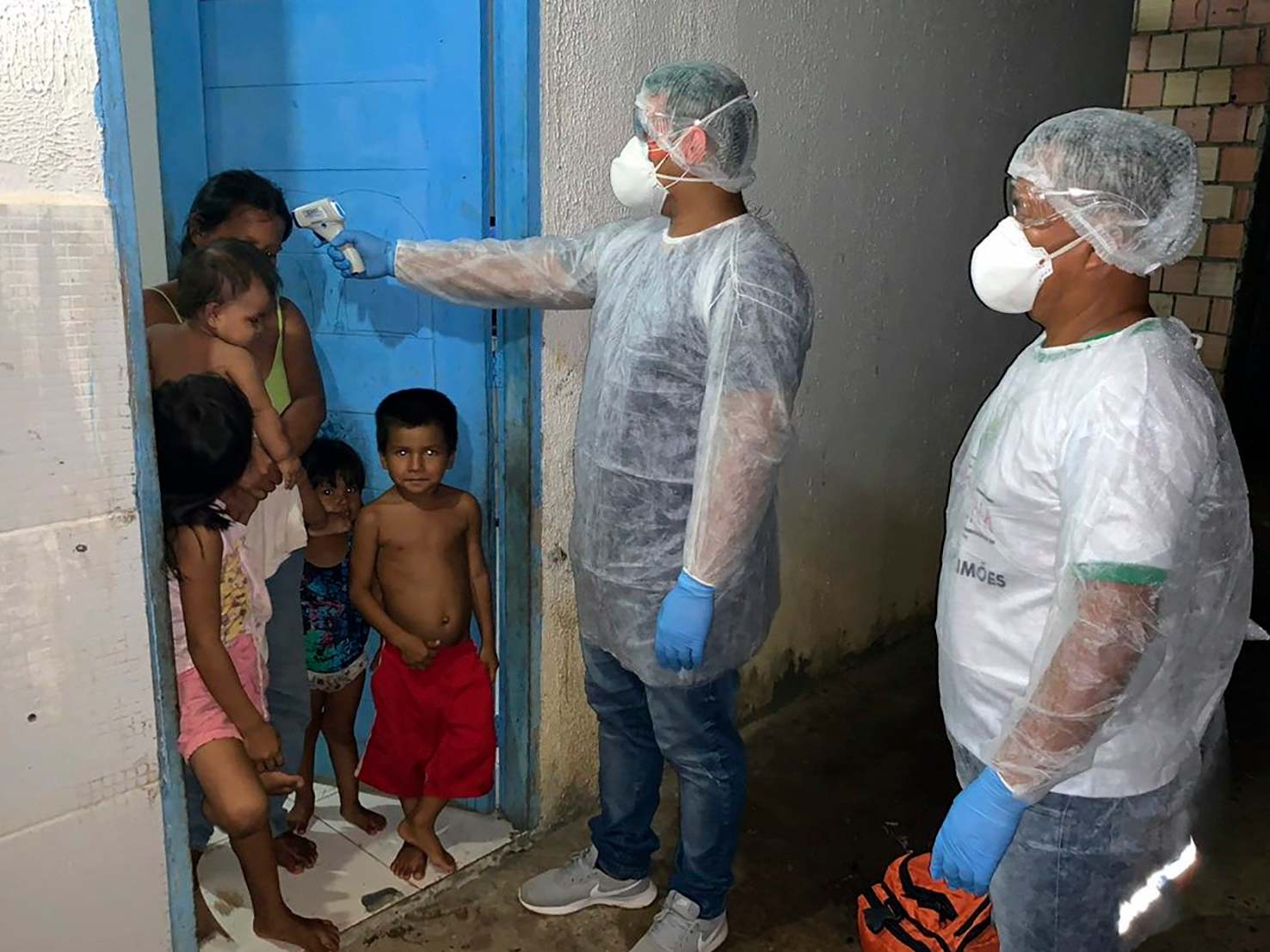 Handout photo released by Brazil's Special Secretariat for Indigenous Health (SESAI) of an employee checking the temperature of members of the Tikuna ethnic group in Lago Grande, Amazonas state