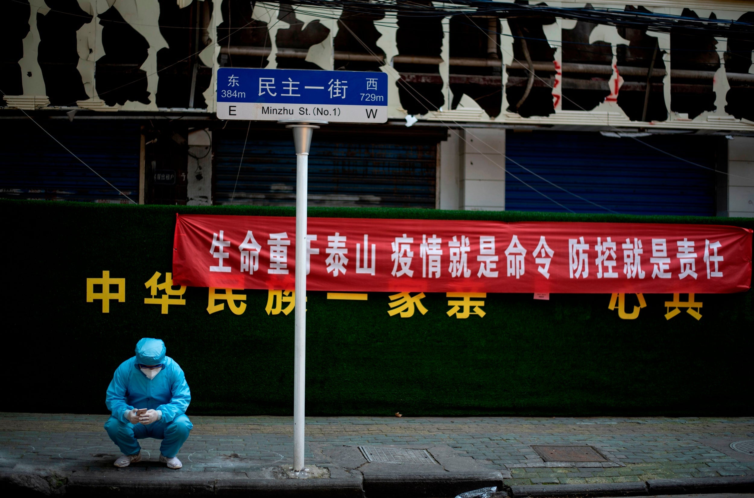 A man wearing personal protective gear uses his phone in Wuhan on Tuesday