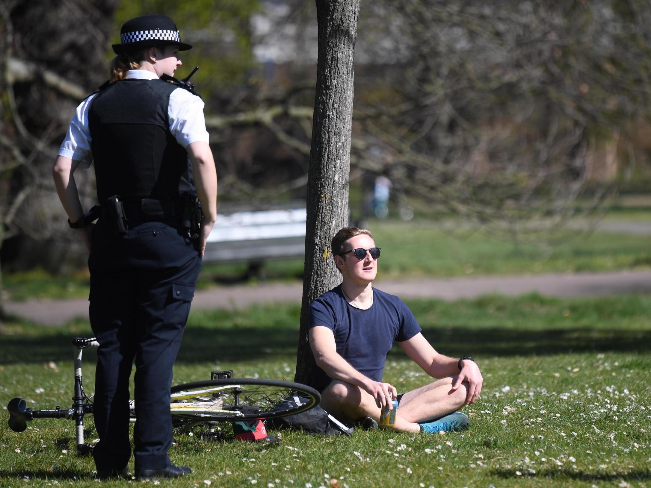 Police speak to people sitting in Greenwich Park in London, 5 April