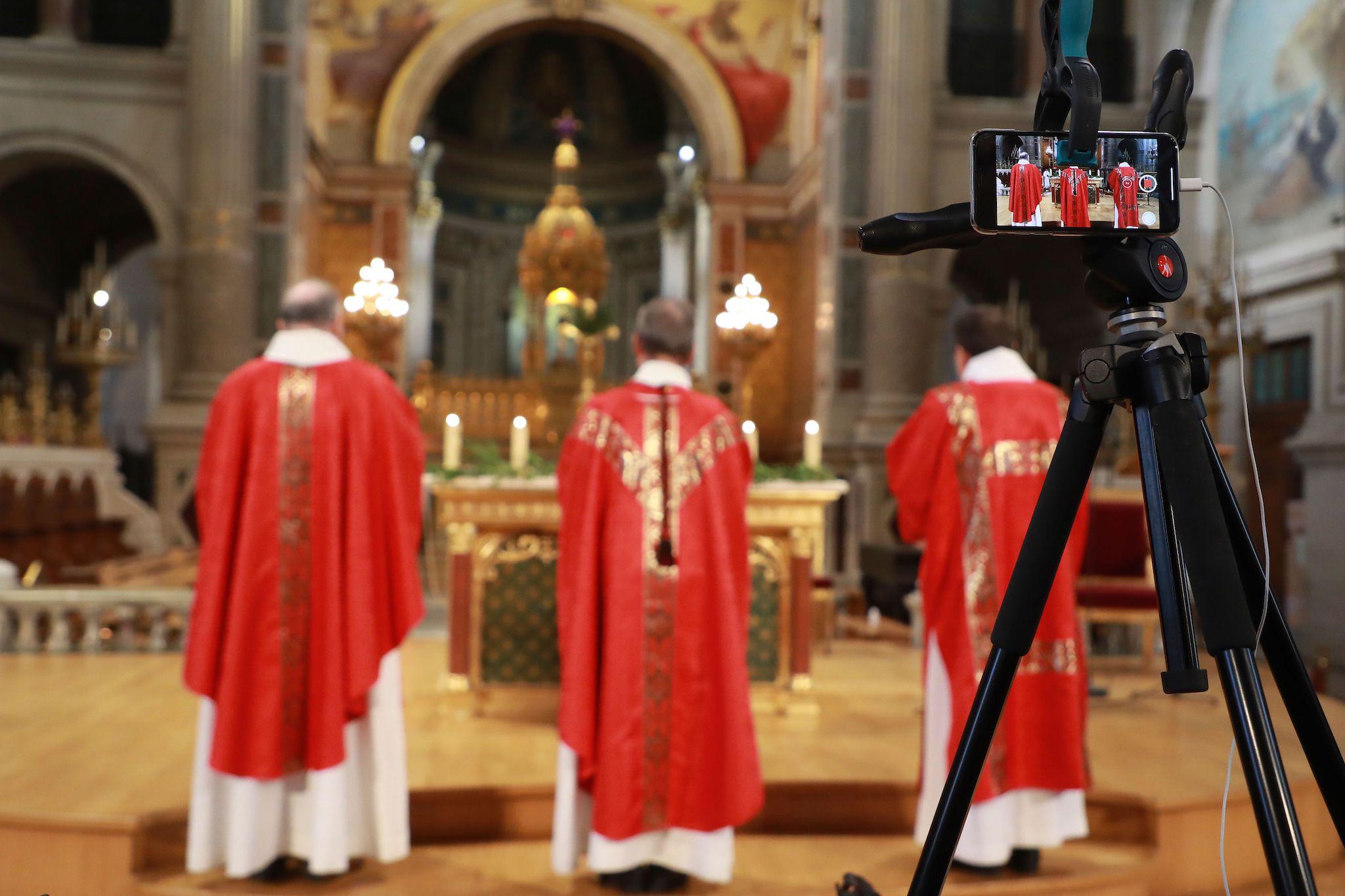 A smartphone records a catholic priest celebrating the palm mass in the empty Saint Francois-Xavier church, which will be broadcasted on social networks