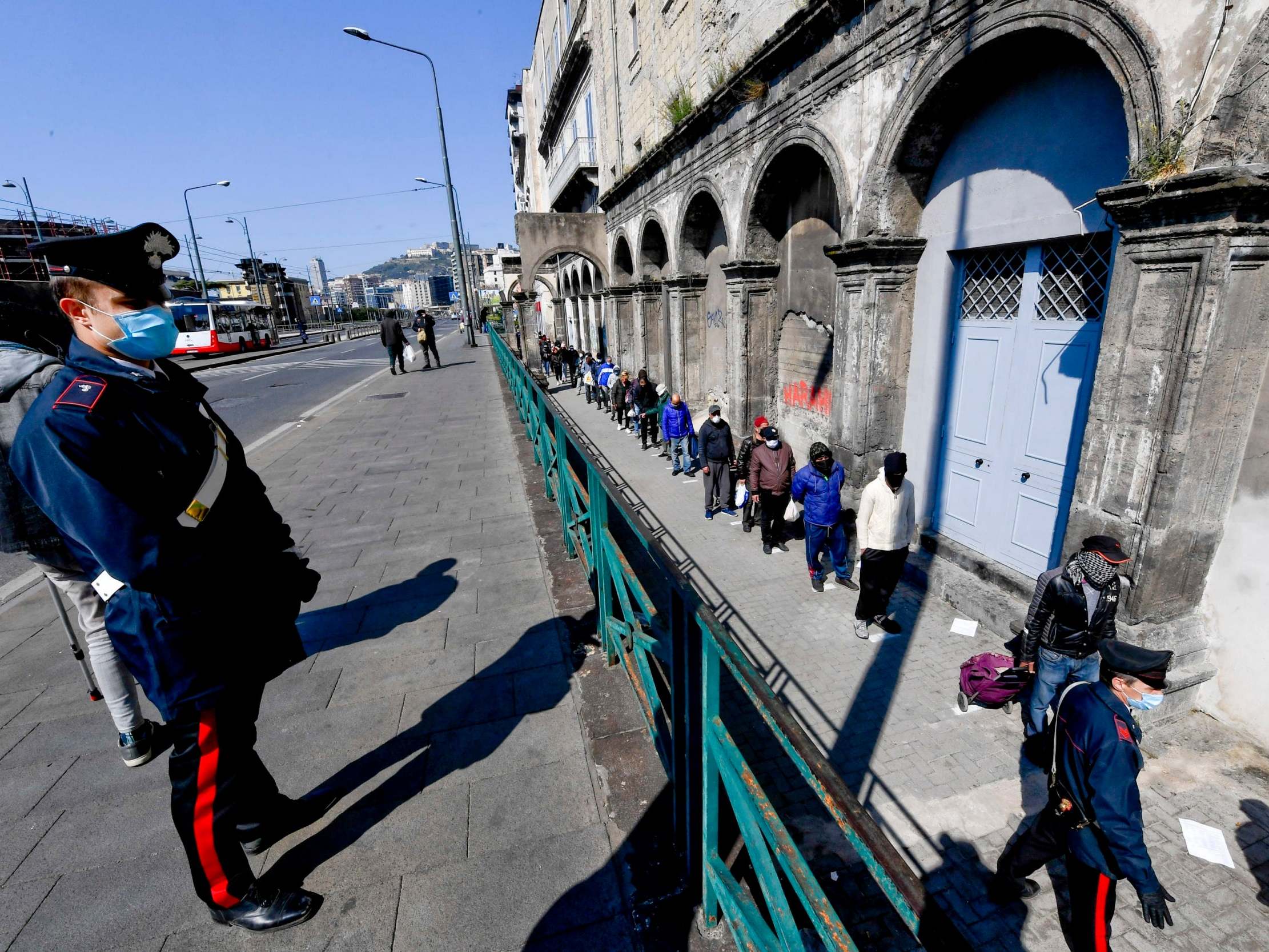 People line up outside a soup kitchen in Naples amid the coronavirus crisis