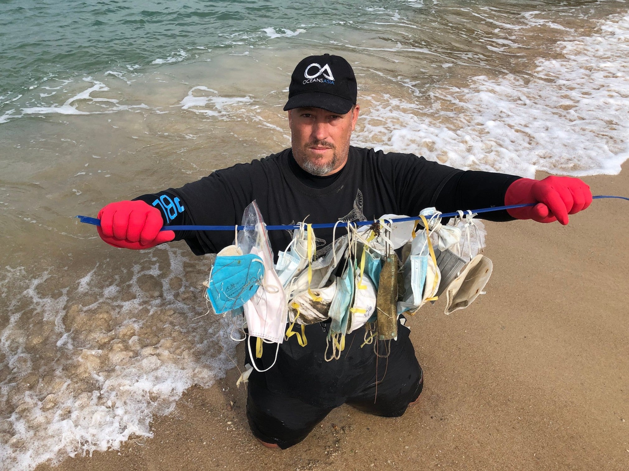 Gary Stokes, co-founder of OceansAsia, holds up the masks he found strewn across beaches near Hong Kong in February 2020