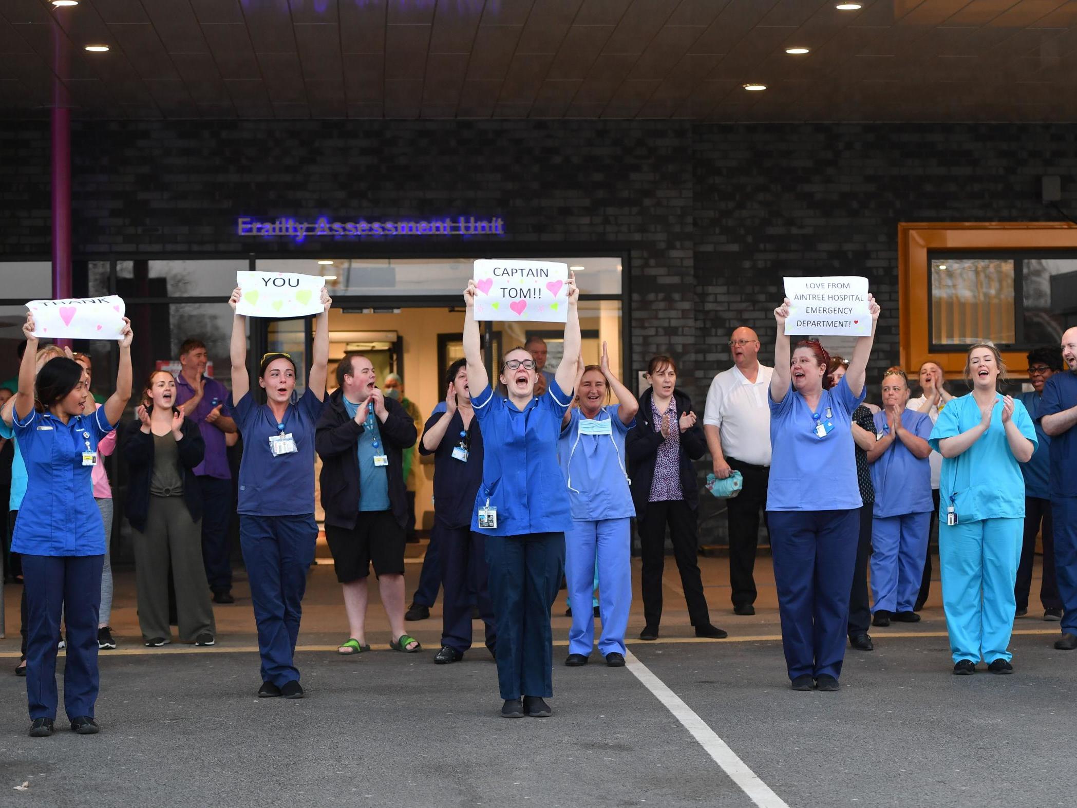 NHS staff hold up signs to thank British veteran Captain Tom Moore who raised over 13 million GBP for the NHS as they take part in a national "clap for carers" in Liverpool on 16 April 2020