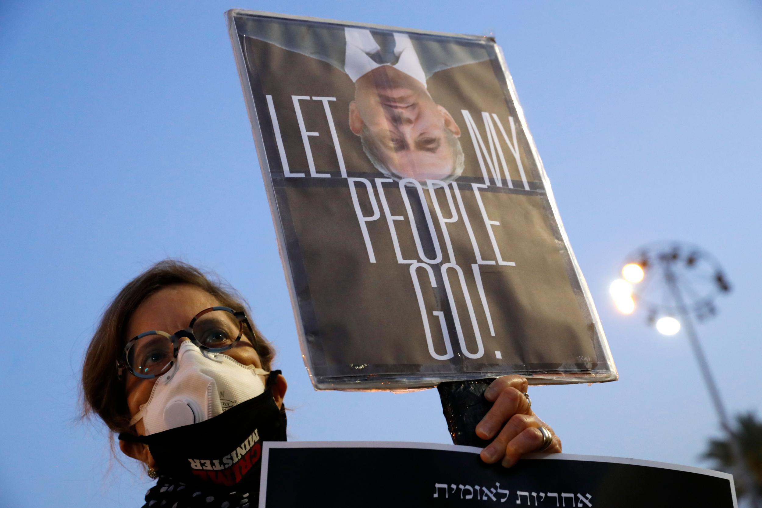 An Israeli woman wearing a face mask with "crime minister" written on it, takes part in a "Black Flag" demonstration against Prime Minister Benjamin Netanyahu