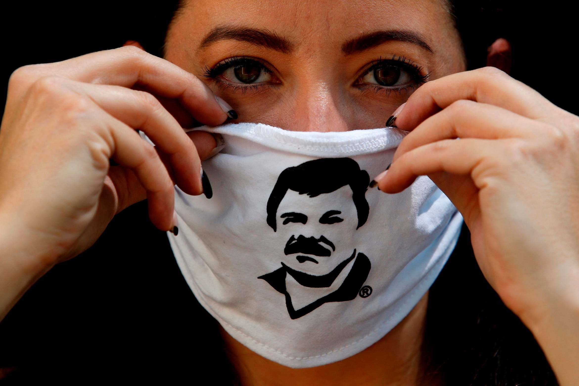 An employee of the Alejandrina Guzman Foundation wears a face mask with the image of Mexican drug lord Joaquin "El Chapo" Guzman - Alejandrina's father - as boxes with basic goods are filled to be donated to people in need