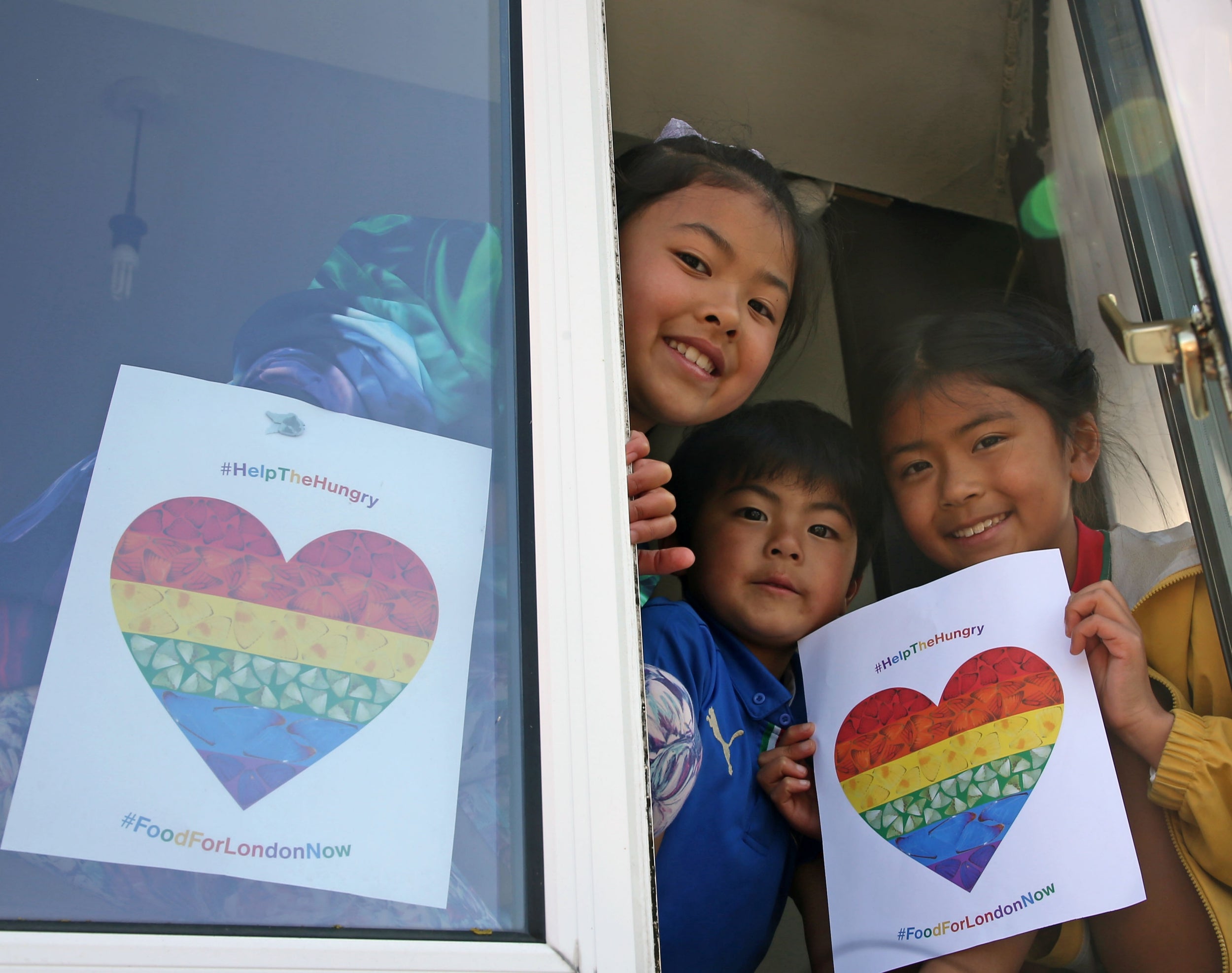 Brothers and sisters, Mei, Rio and Jui, proudly hold up Help The Hungry posters