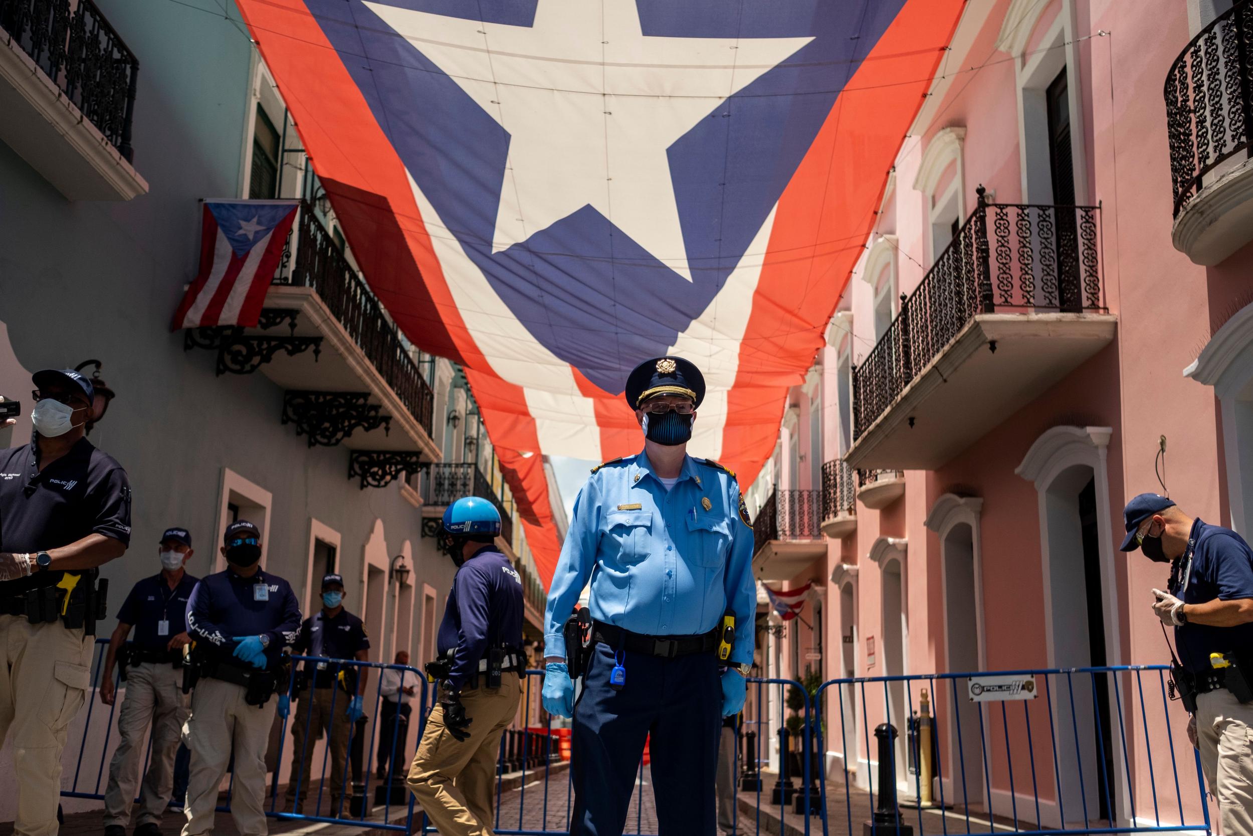 Puerto Rico police officers stand in front of the governor’s mansion as hundreds of private and municipal paramedics protest in their ambulances through Old San Juan