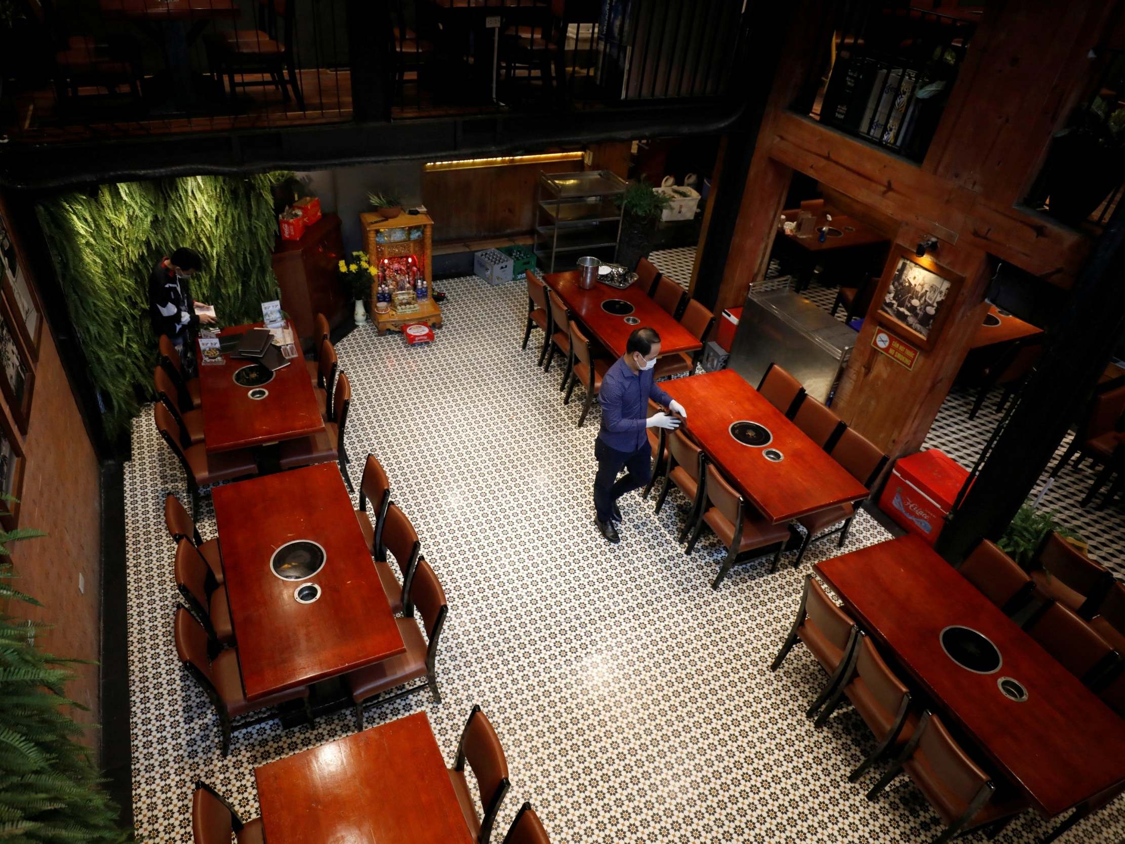 A man wears a protective face mask as he cleans tables for the reopening of Vua Cha Ca fish cake restaurant after the government eased nationwide lockdown