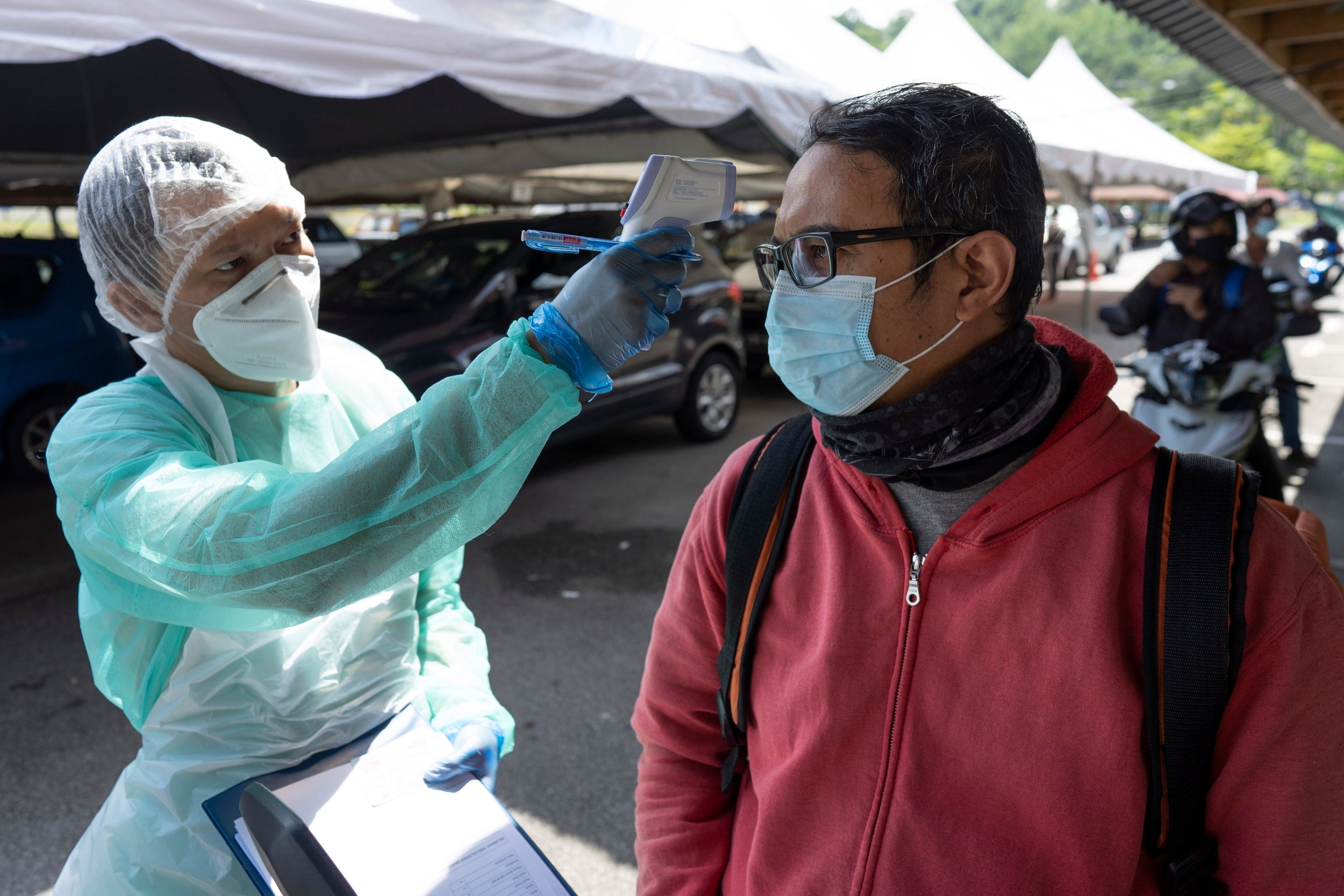 A health worker checks the temperature of a man during coronavirus testing in Kuala Lumpur