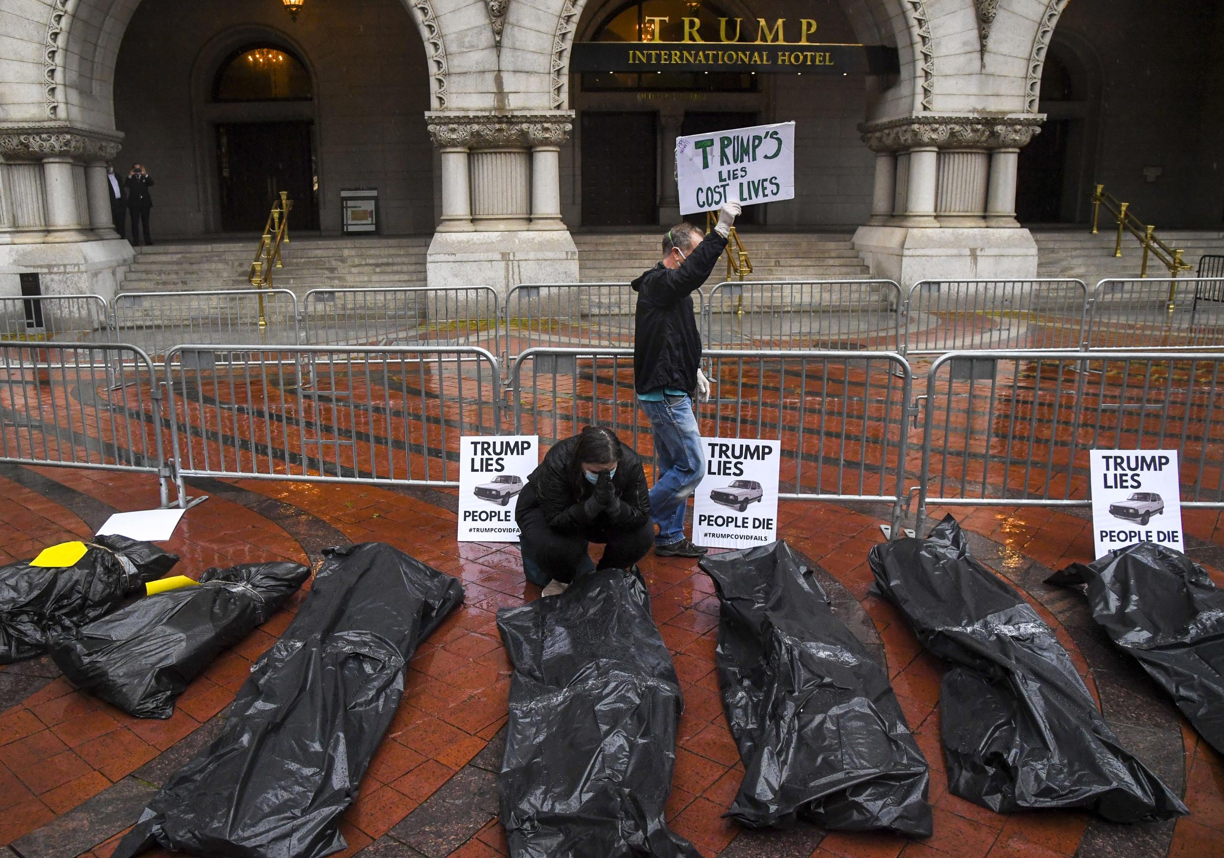 Melissa Byrne, with a group calling themselves The People’s Motorcade, prays in front of replicas of body bags placed on the sidewalk in front of the Trump International Hotel in Washington