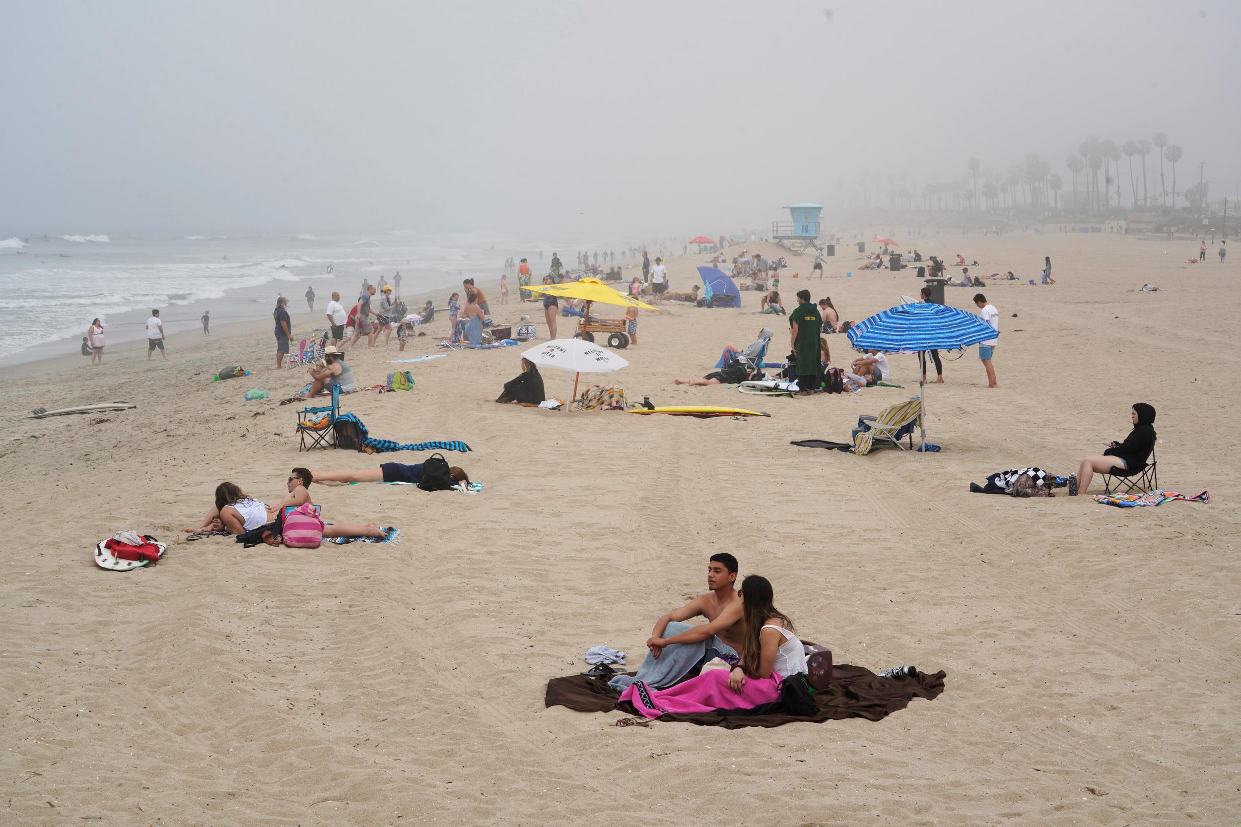 People sit in groups at Huntington City Beach during the outbreak of the coronavirus disease (COVID-19) in Huntington Beach, California,