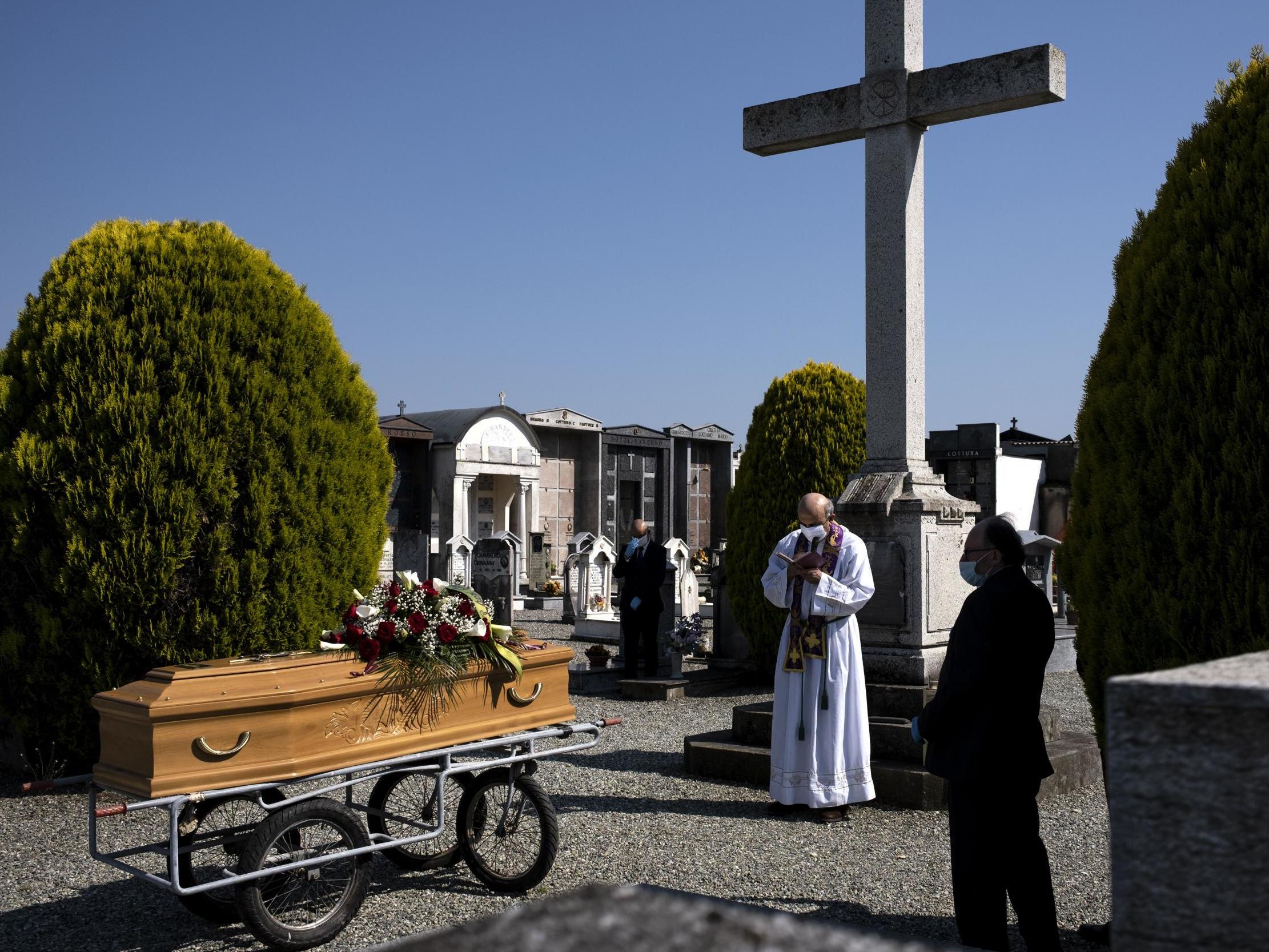 A priest reads the book of funeral rites and common prayers during a funeral service for a victim of Covid-19 at a cemetery in Piedmont in April (Marco Bertorello/AFP via Getty)