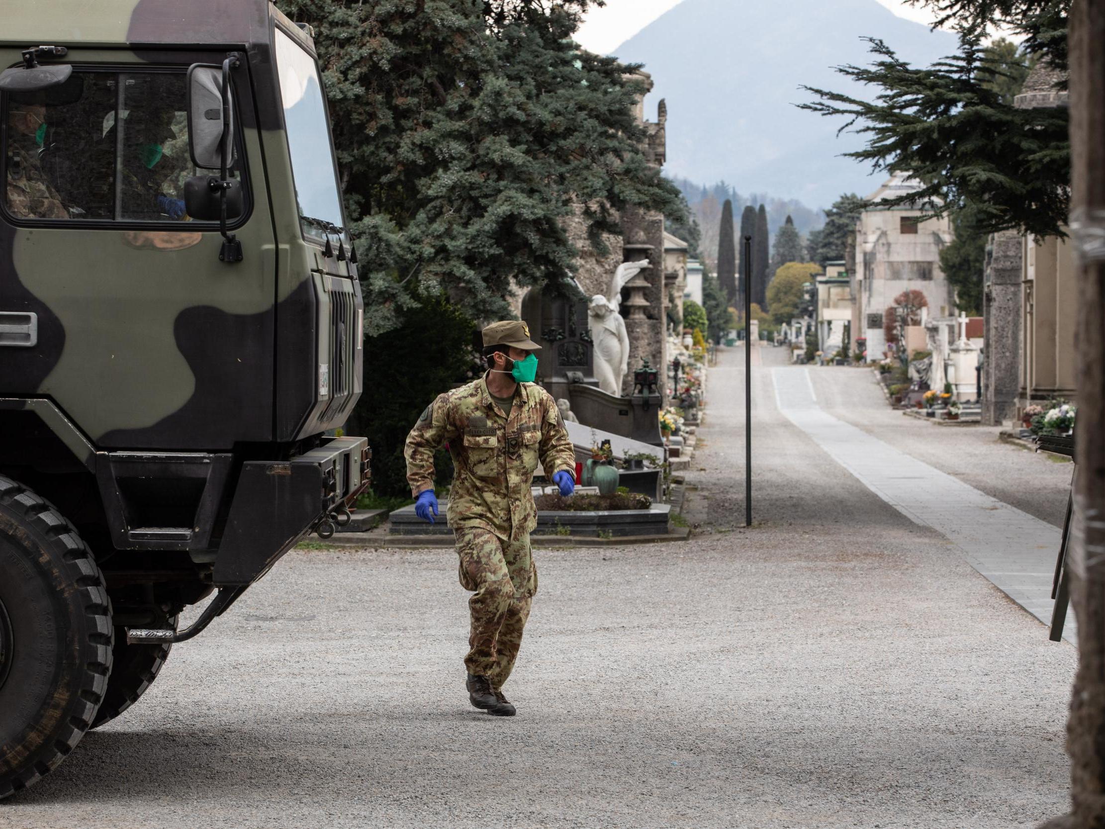 An Italian army officer runs past a military vehicle parked in the Monumental Cemetery in Bergamo during the coronavirus crisis (Emanuele Cremaschi/Getty)