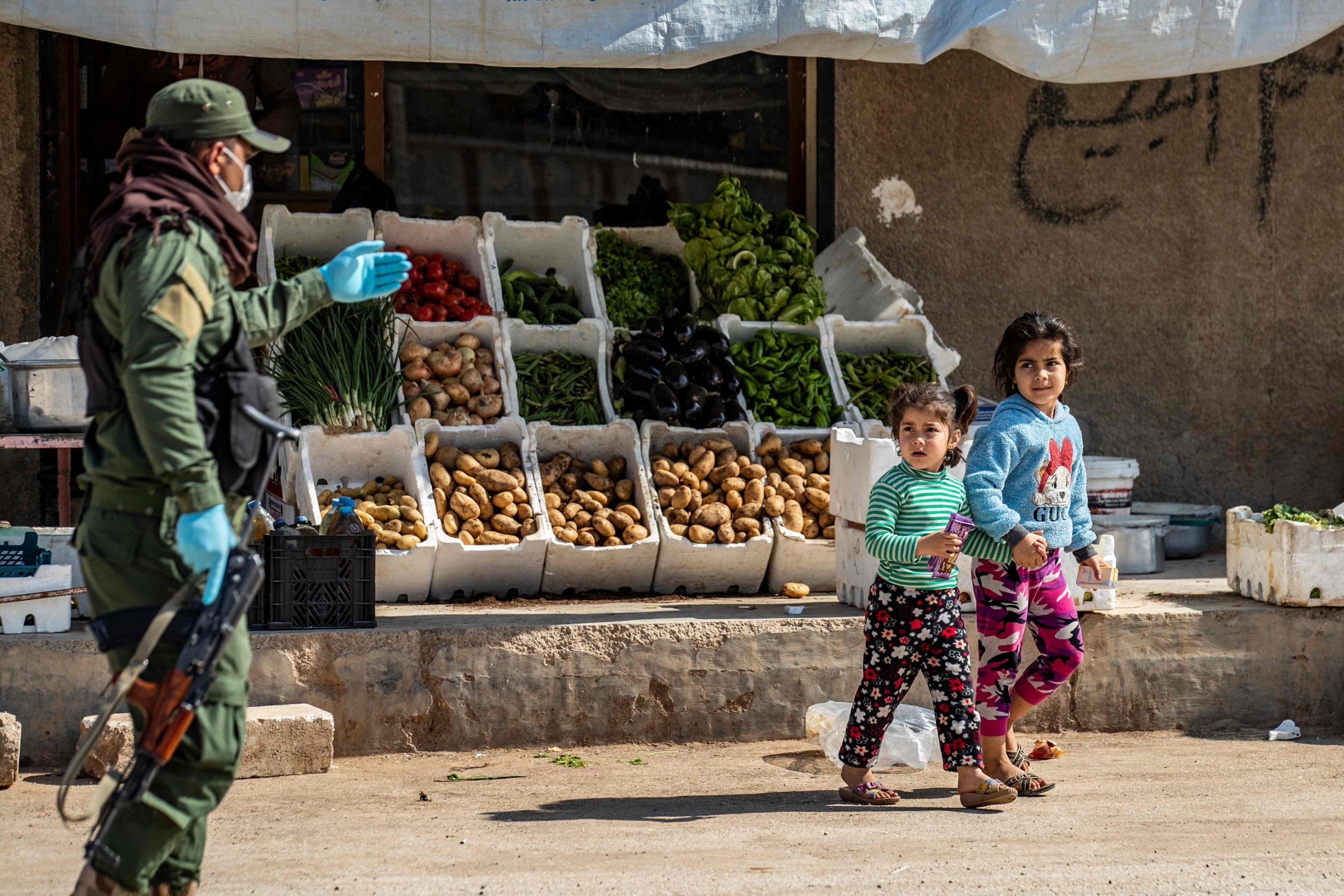A member of the Kurdish Internal Security Forces urges children to return home in Syria's northeastern city of Hasakeh on Thursday 30 April