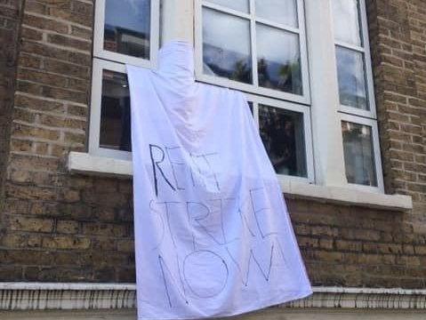 A white sheet bearing the slogan ‘rent strike now’ hangs from a window in Hackney, east London (Rent Strike London)