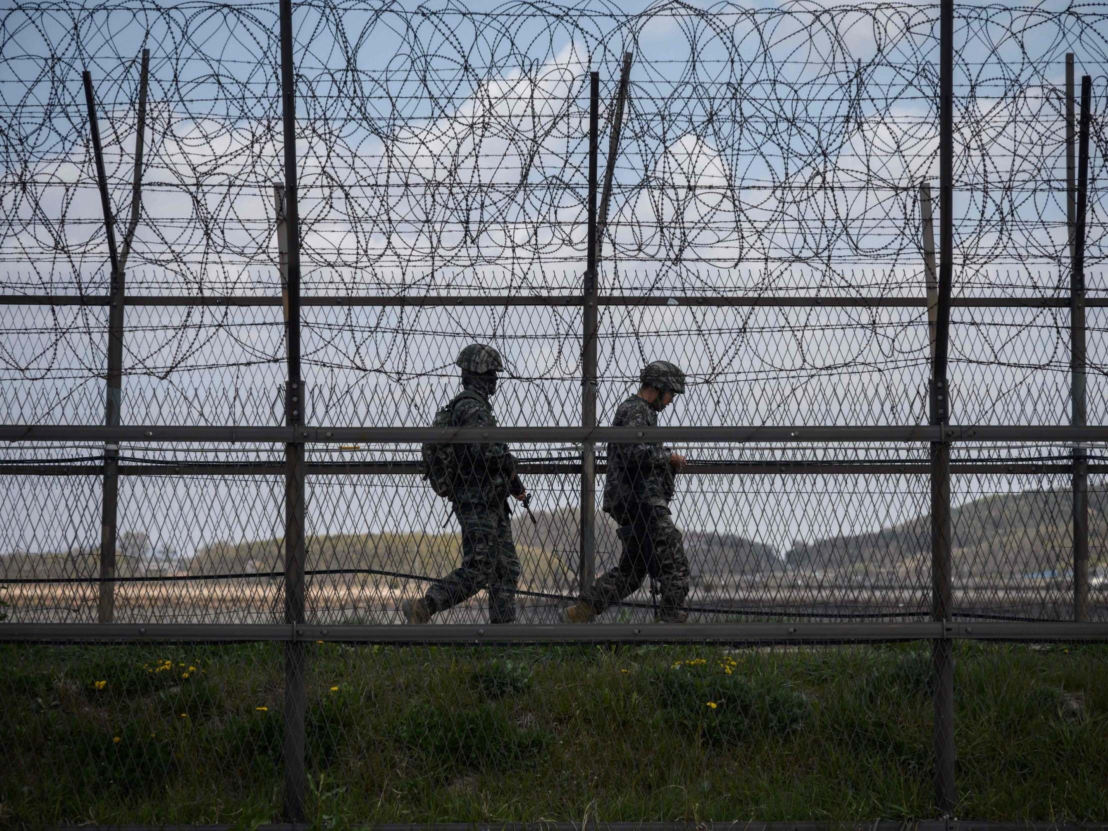 South Korean soldiers patrolling along a barbed wire fence separating North and South Korea