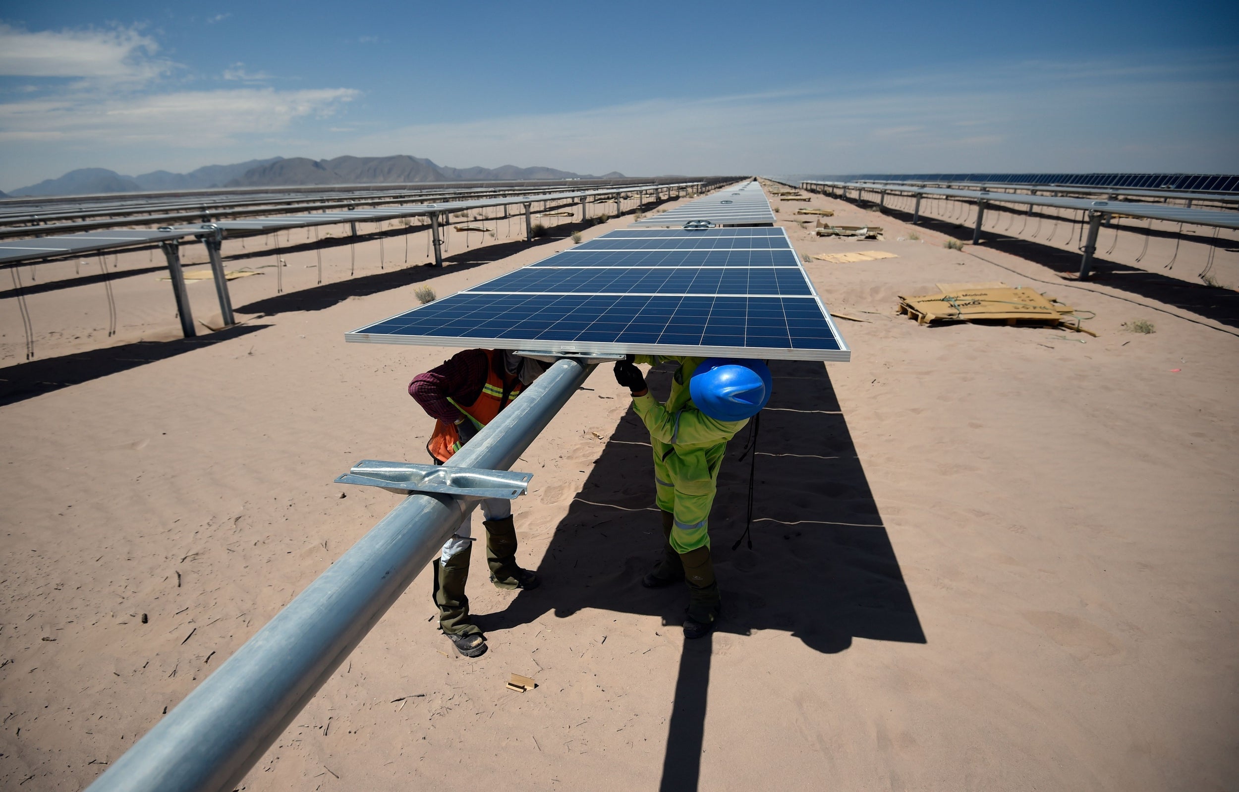 Workers install solar panels at the Enel Green Power photovoltaic plant in the desert near Villanueva, Mexico