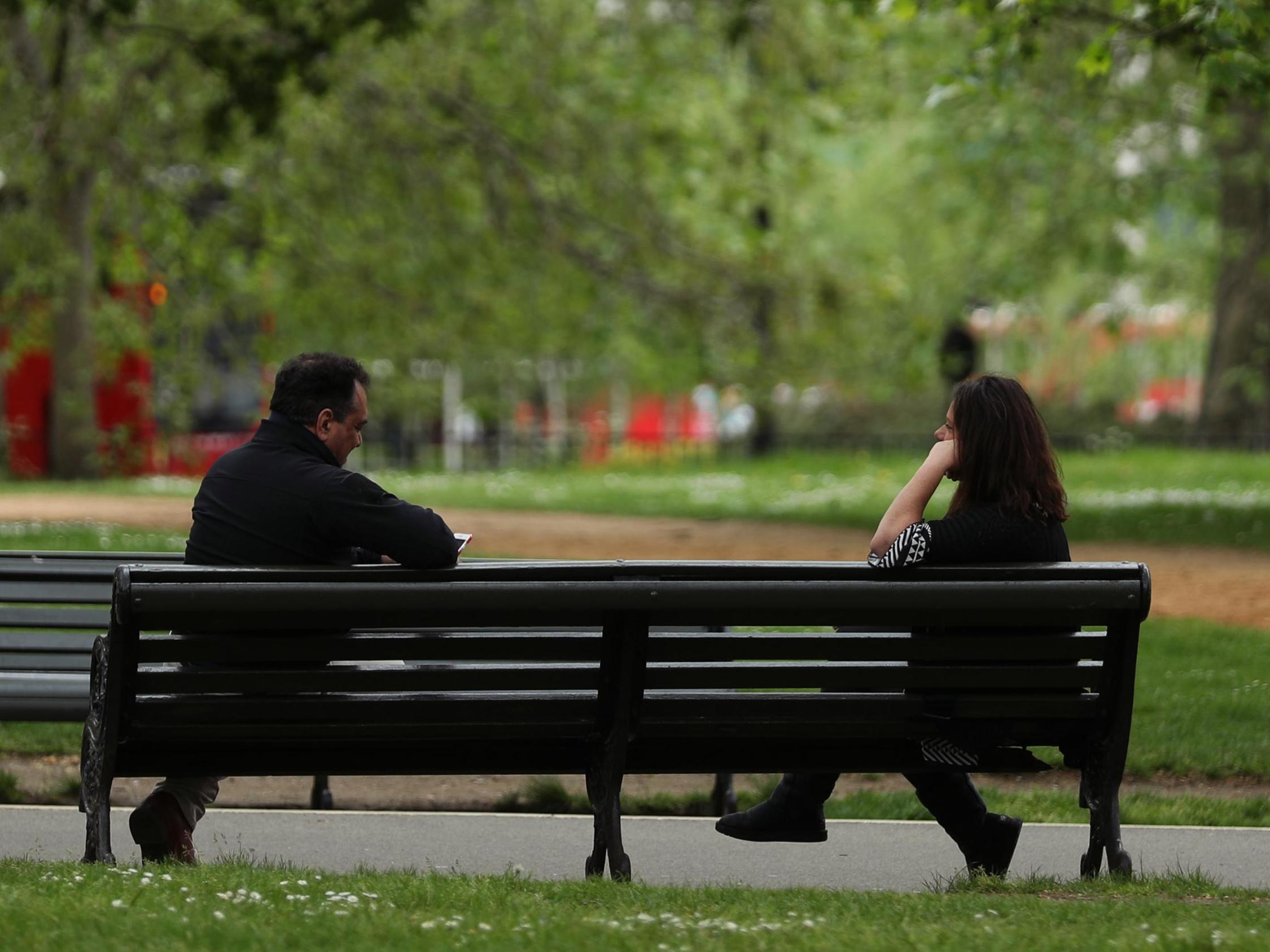 People observing social distancing on a bench in Hyde Park, London