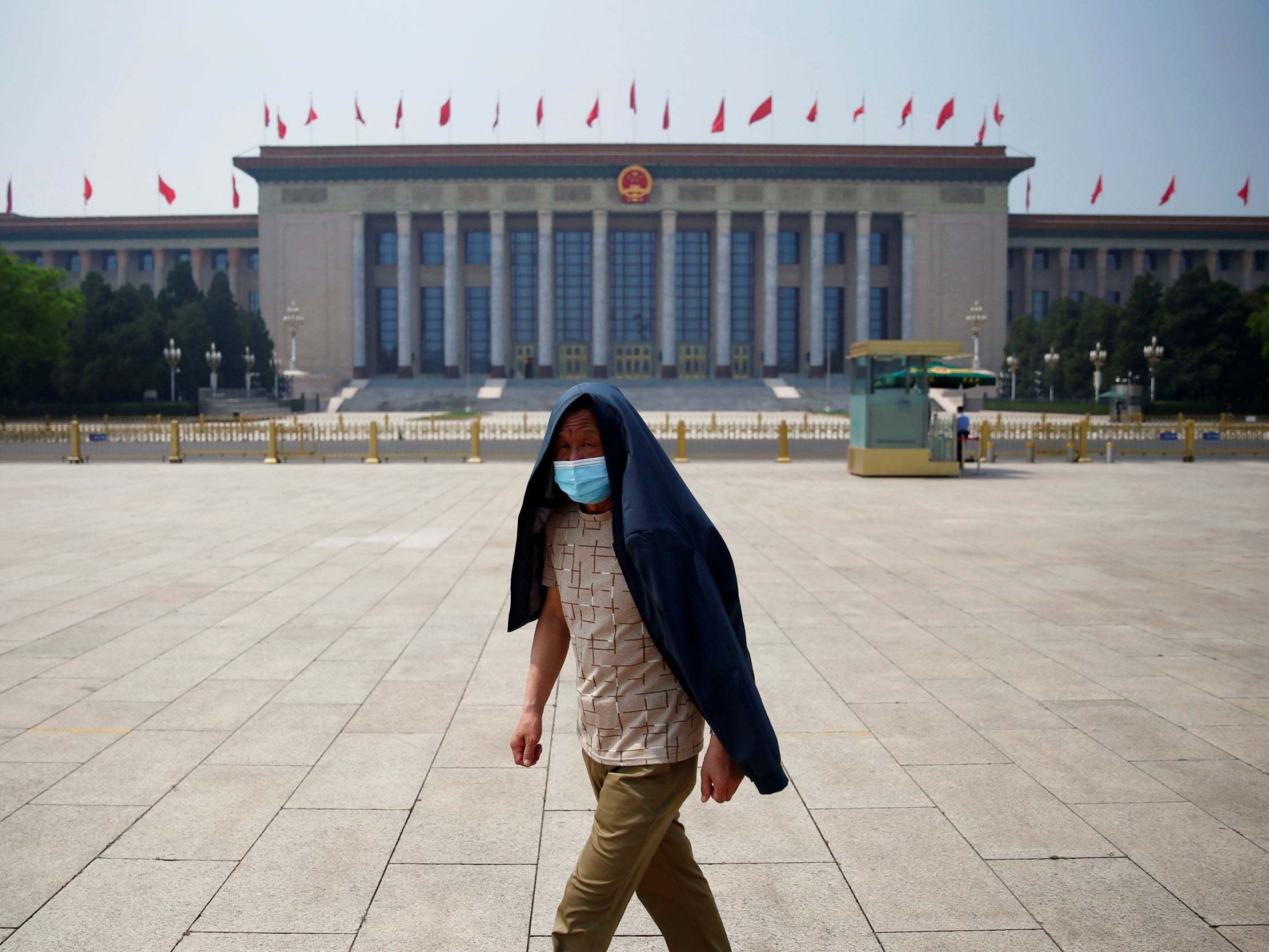 A man wearing a face mask walks through Tiananmen Square