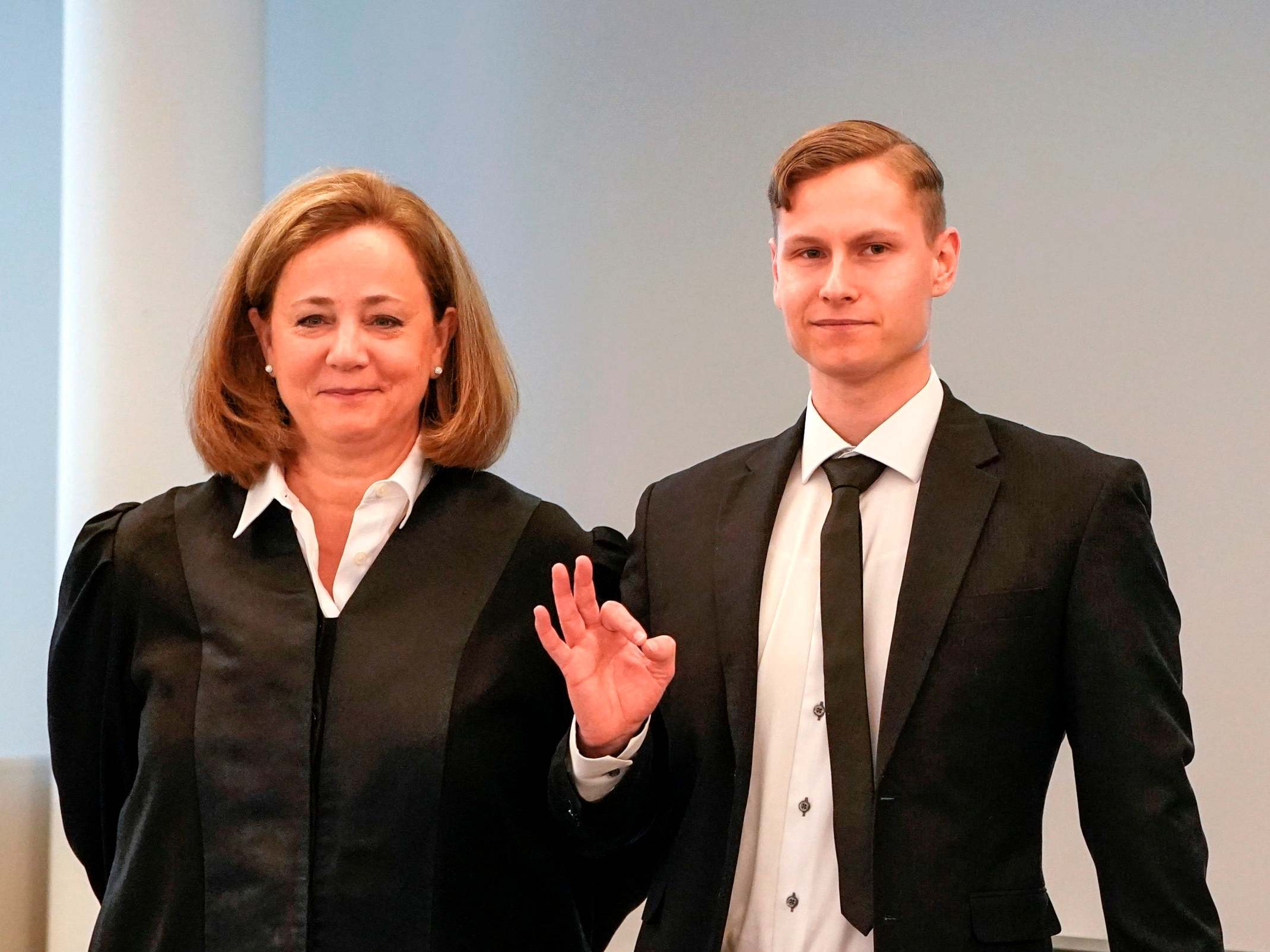 Manshaus arrives at court, using an OK hand sign to signify white power