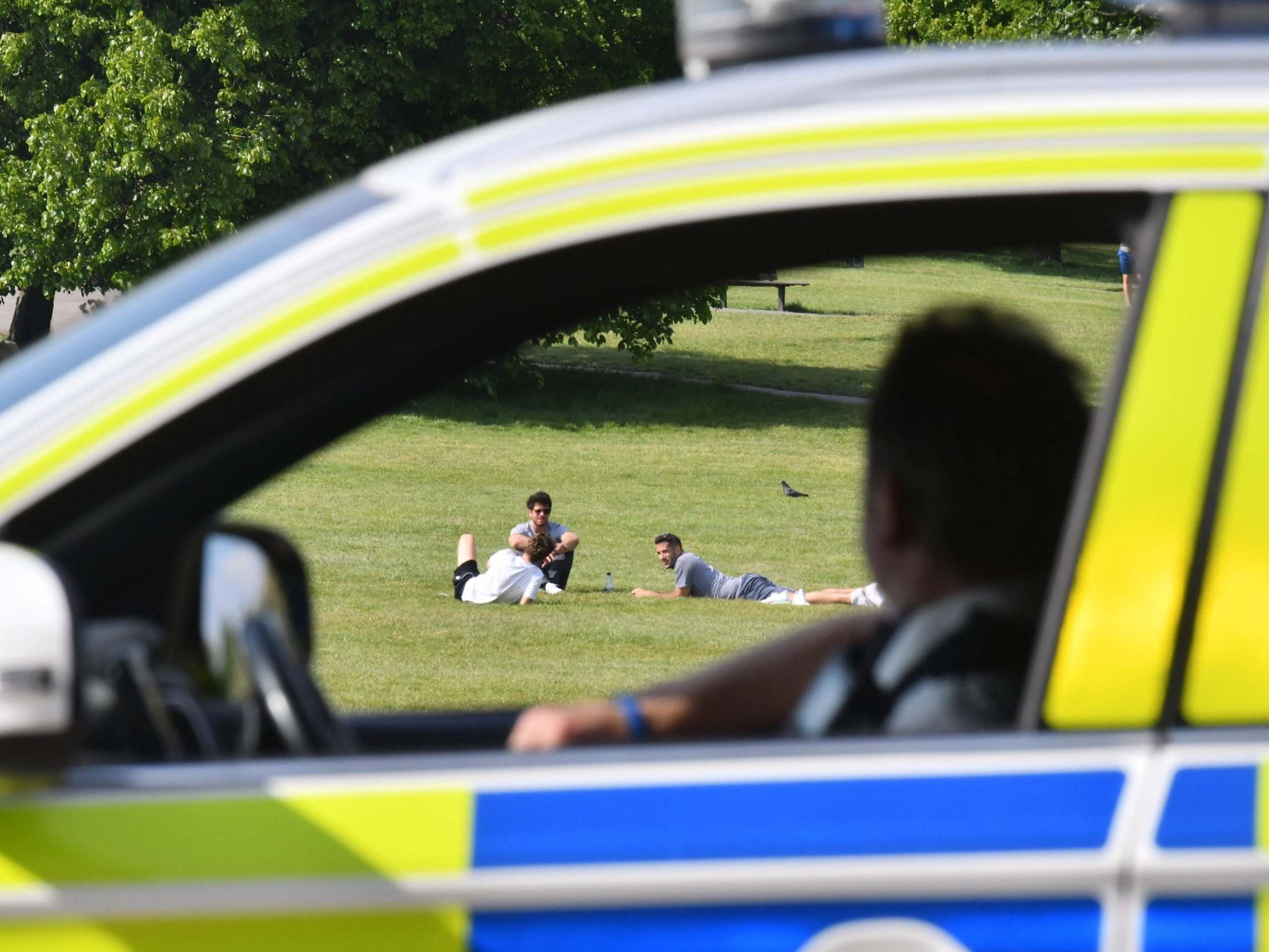 Police officers look at people relaxing in the sunshine on Primrose Hill in London on 7 May