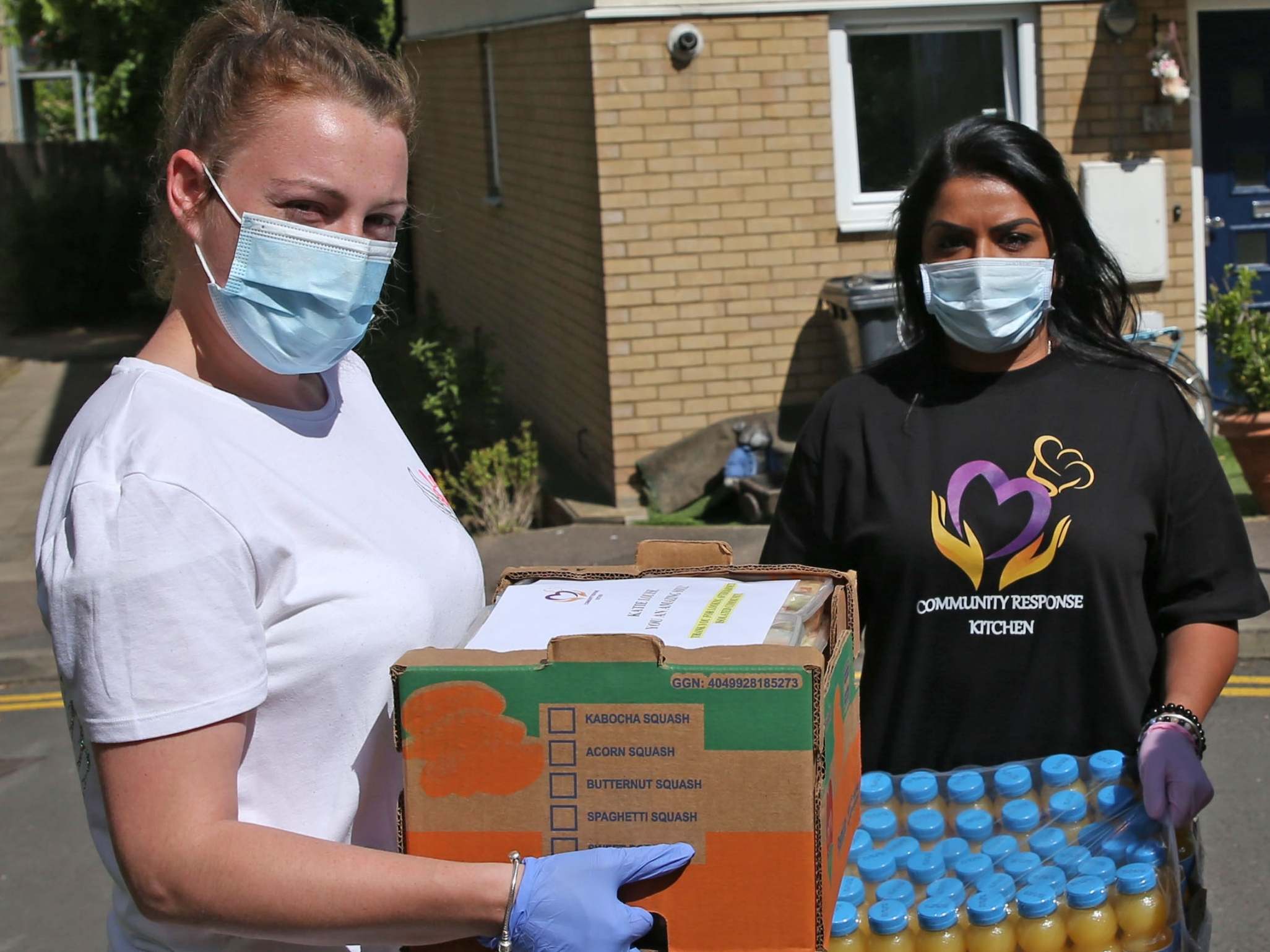 Katie-Louise Barber (left) and a fellow volunteer deliver food to neighbours in need