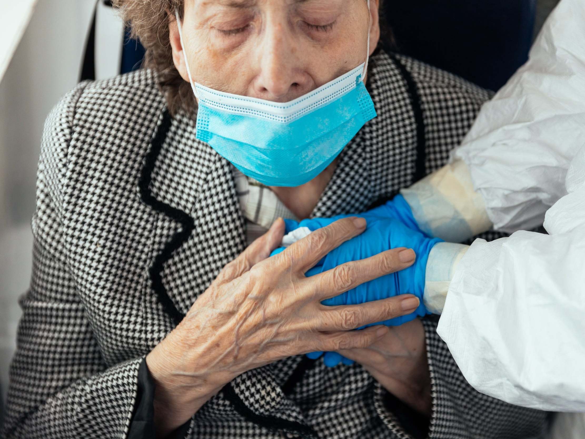 An elderly woman with Covid-19 holds the hands of a Spanish Red Cross volunteer in Zaragoza, Spain, 28 April 2020.