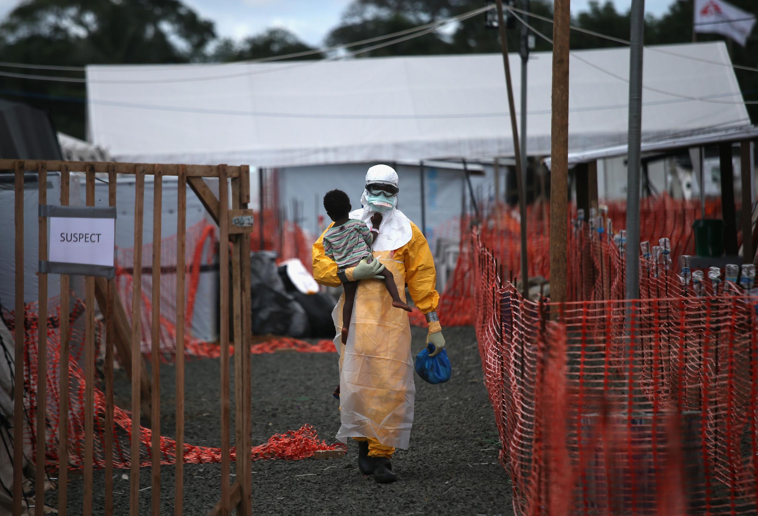 A Médecins Sans Frontières worker carries a child suspected of having Ebola to an MSF treatment centre in Liberia