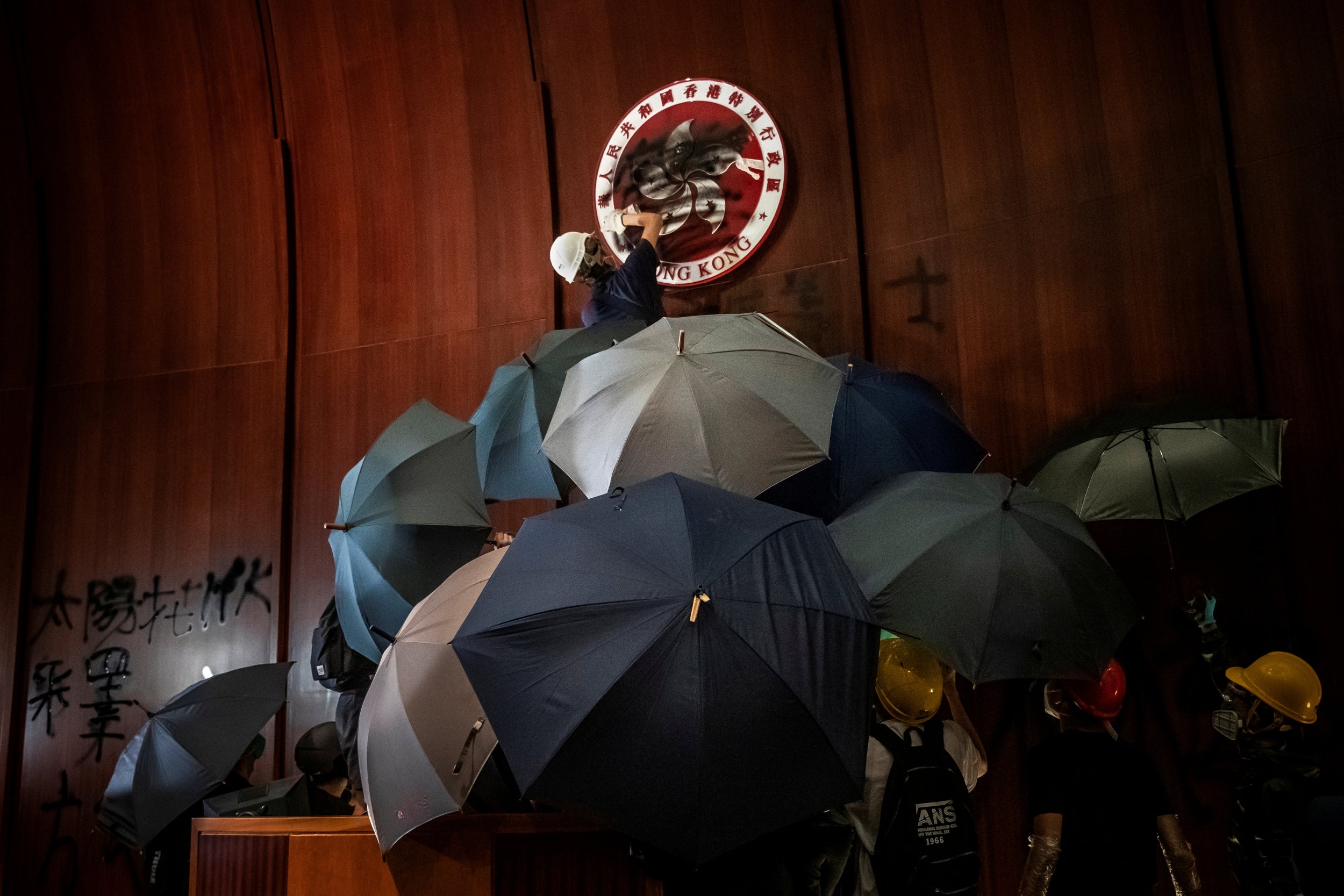 A man sprays paint over the Regional Emblem of Hong Kong after anti-extradition bill protesters stormed the Legislative Council Complex on the 22nd anniversary of the handover from British to Chinese rule, destroying pictures and daubing walls with graffiti on 1 July, 2019