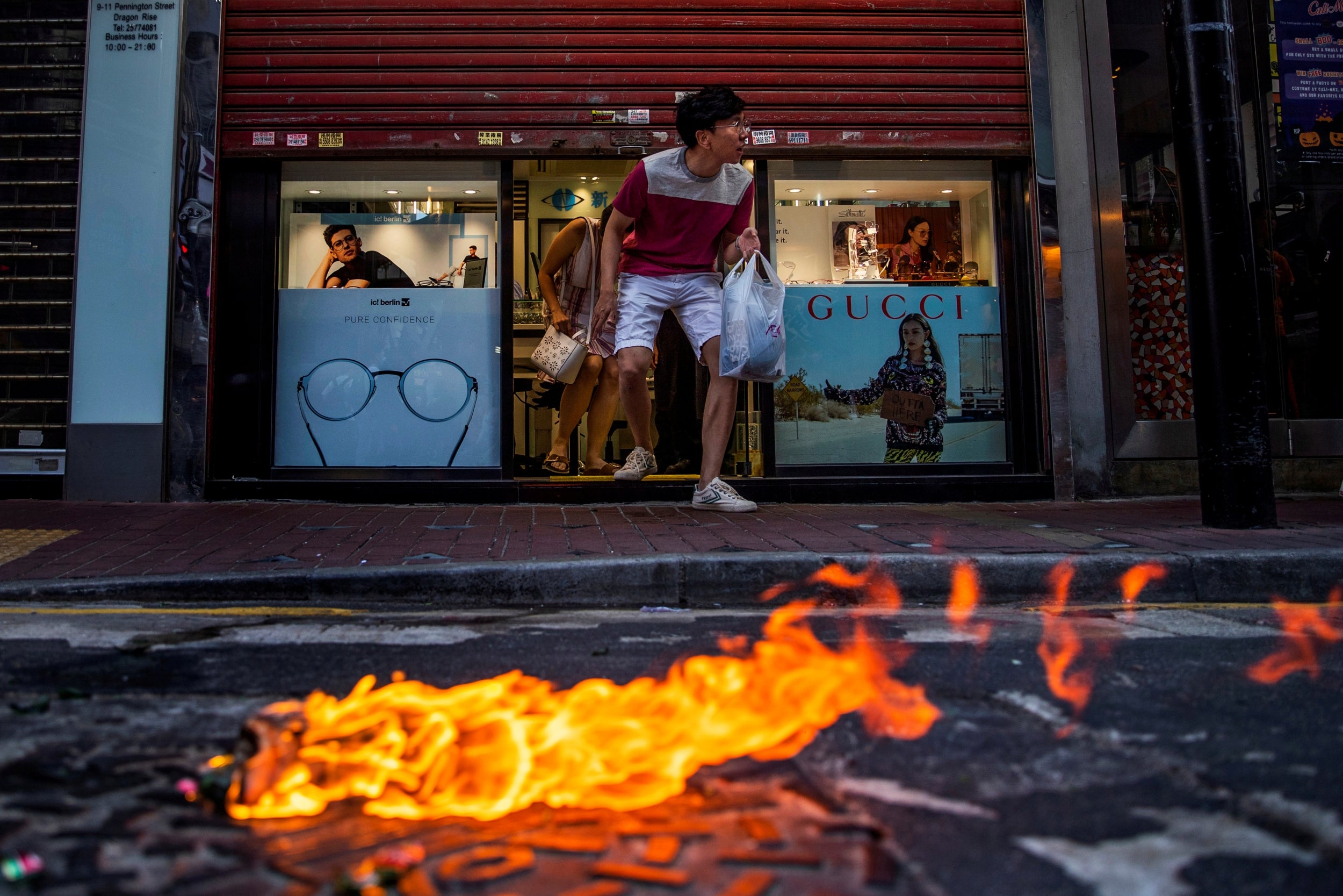 Customers flee from an opticians while a molotov cocktail burns