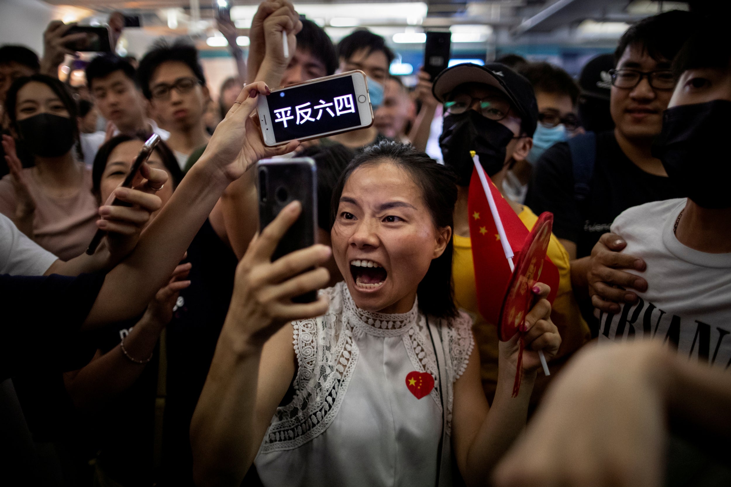 A pro-China demonstrator films herself as an anti-government protester holds up a sign on her phone during skirmishes between the two opposing groups at Yuen Long station in Hong Kong, China, 12 September, 2019. The words on the phone read, "Seek an official reassessment of the June 4 crackdown," referring to the 1989 Tiananmen Square protests