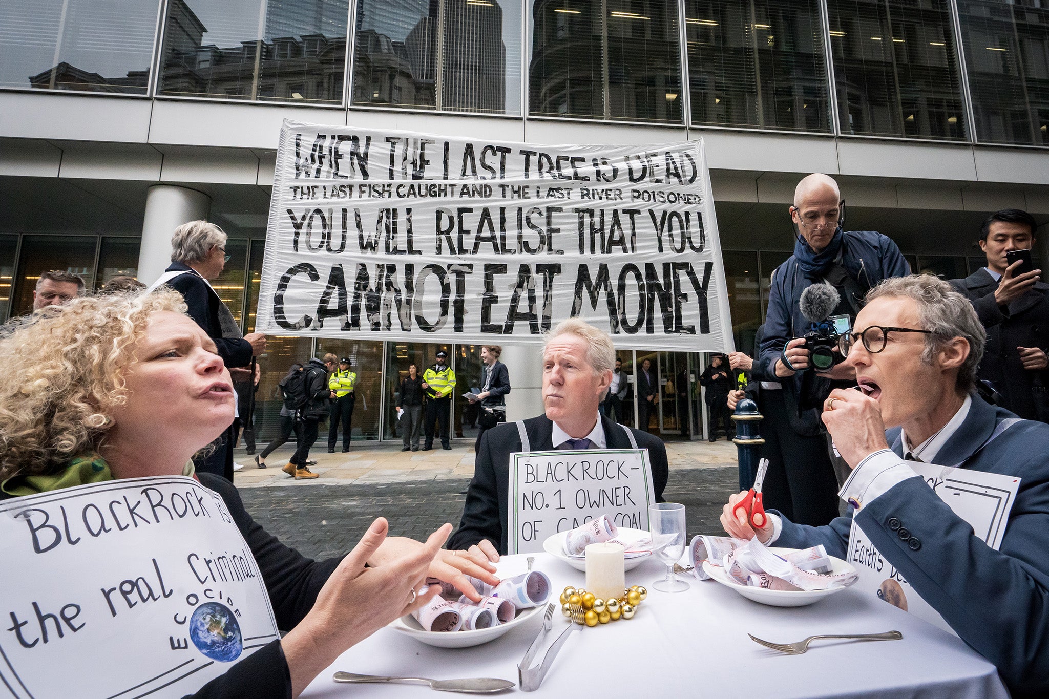 Protestors eat fake money outside the headquarters of Blackrock to protest the damage caused to the Amazon basin through the firm’s investments