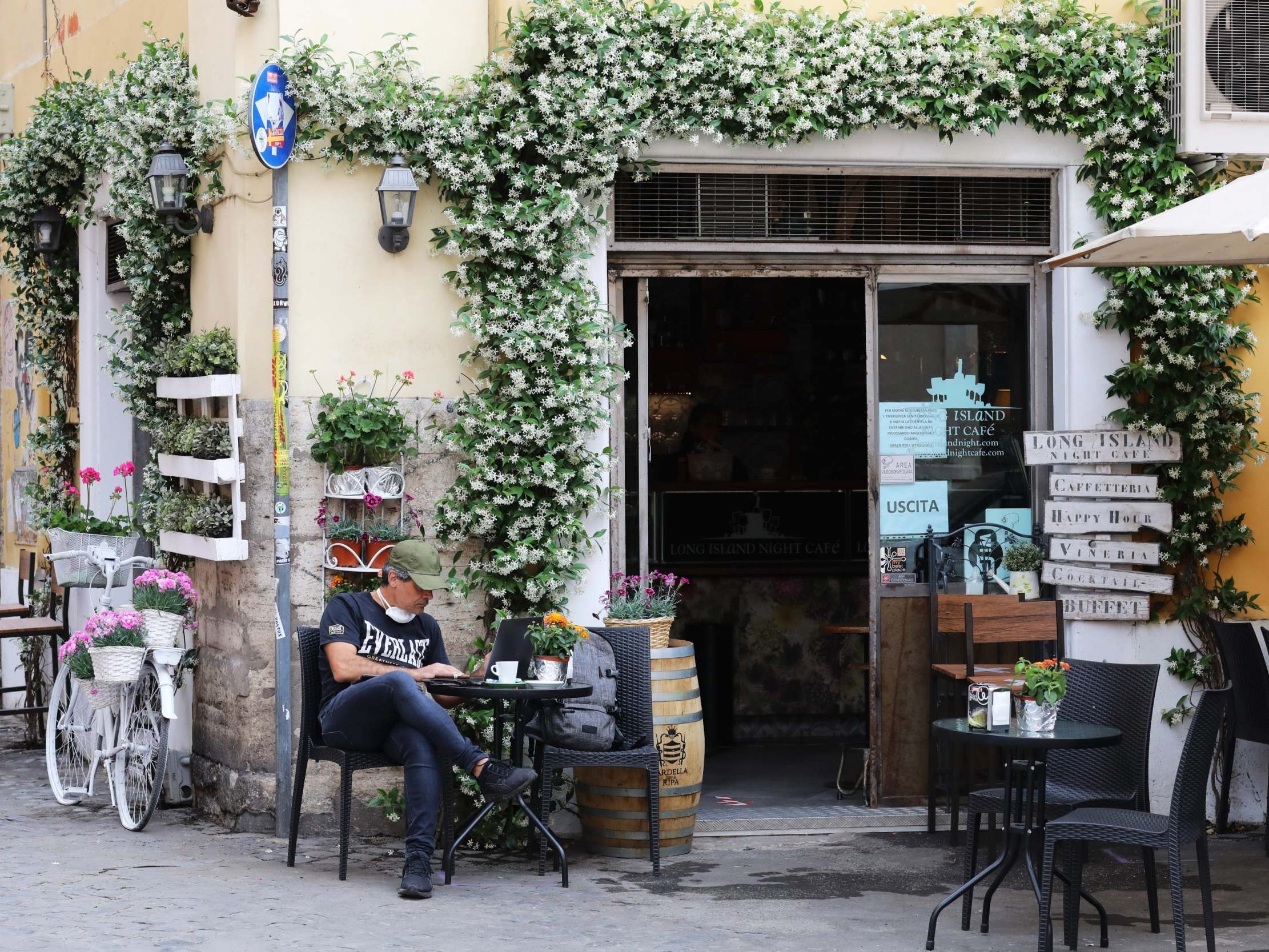 A man sits outside a bar in the Trastevere district of Rome