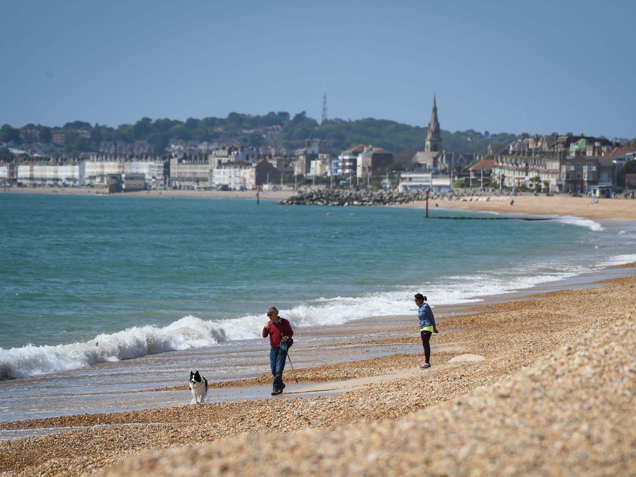 A man walks his dog on Preston beach in Weymouth on Sunday