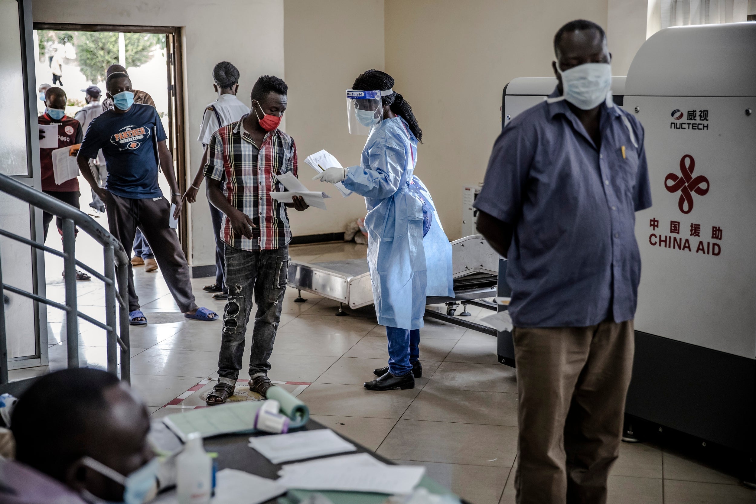 A Kenyan healthcare worker speaks with a truck driver waiting for his clearance certificate (The Washington Post)