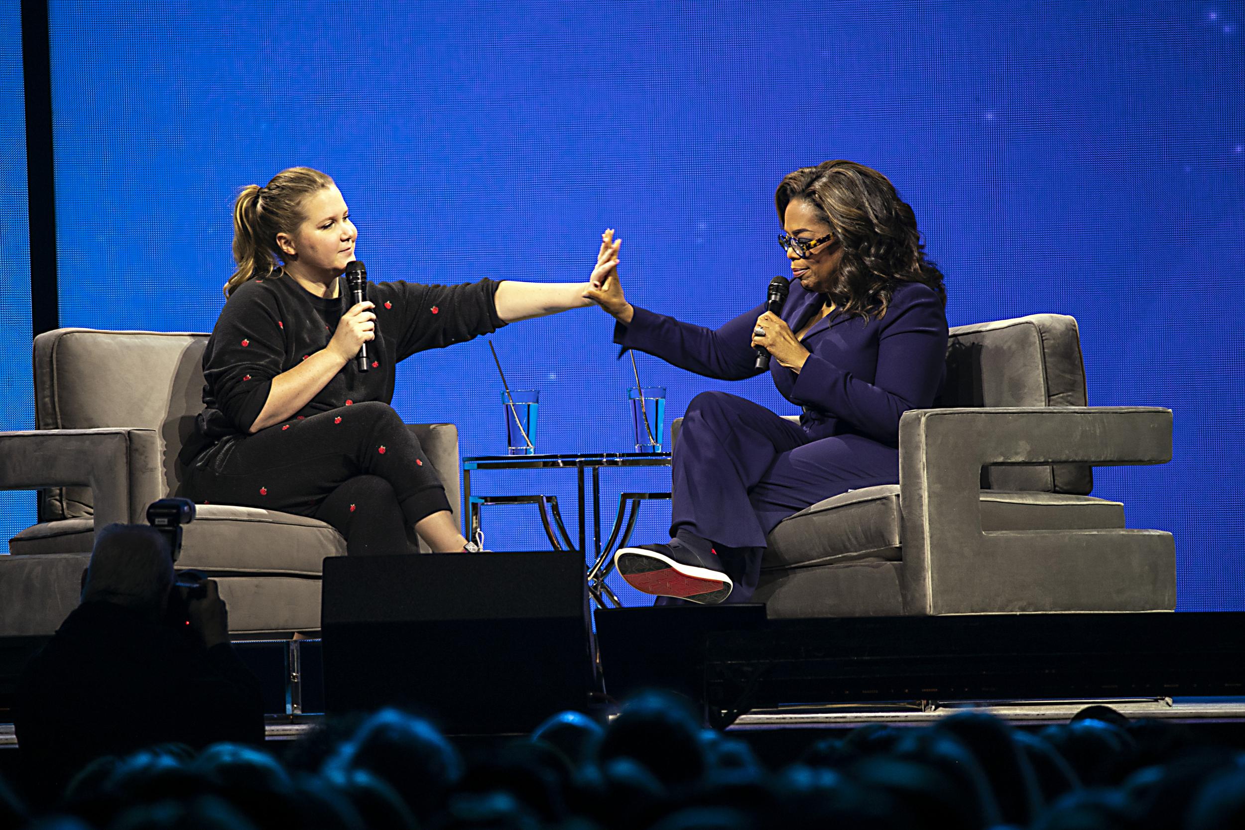 Schumer and Oprah Winfrey share a moment on stage during Oprah’s 2020 Vision: Your Life in Focus Tour