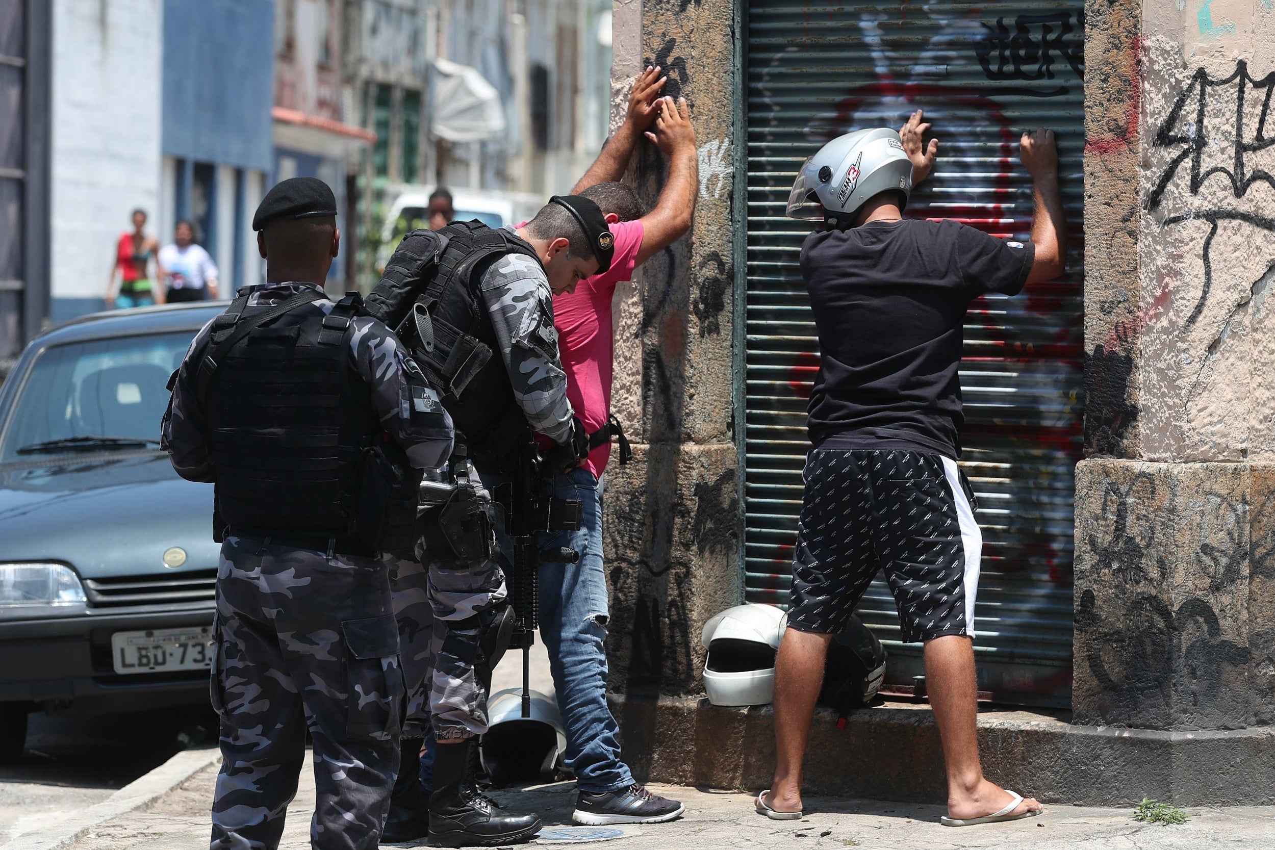 Officers make suspected criminals stand against a wall