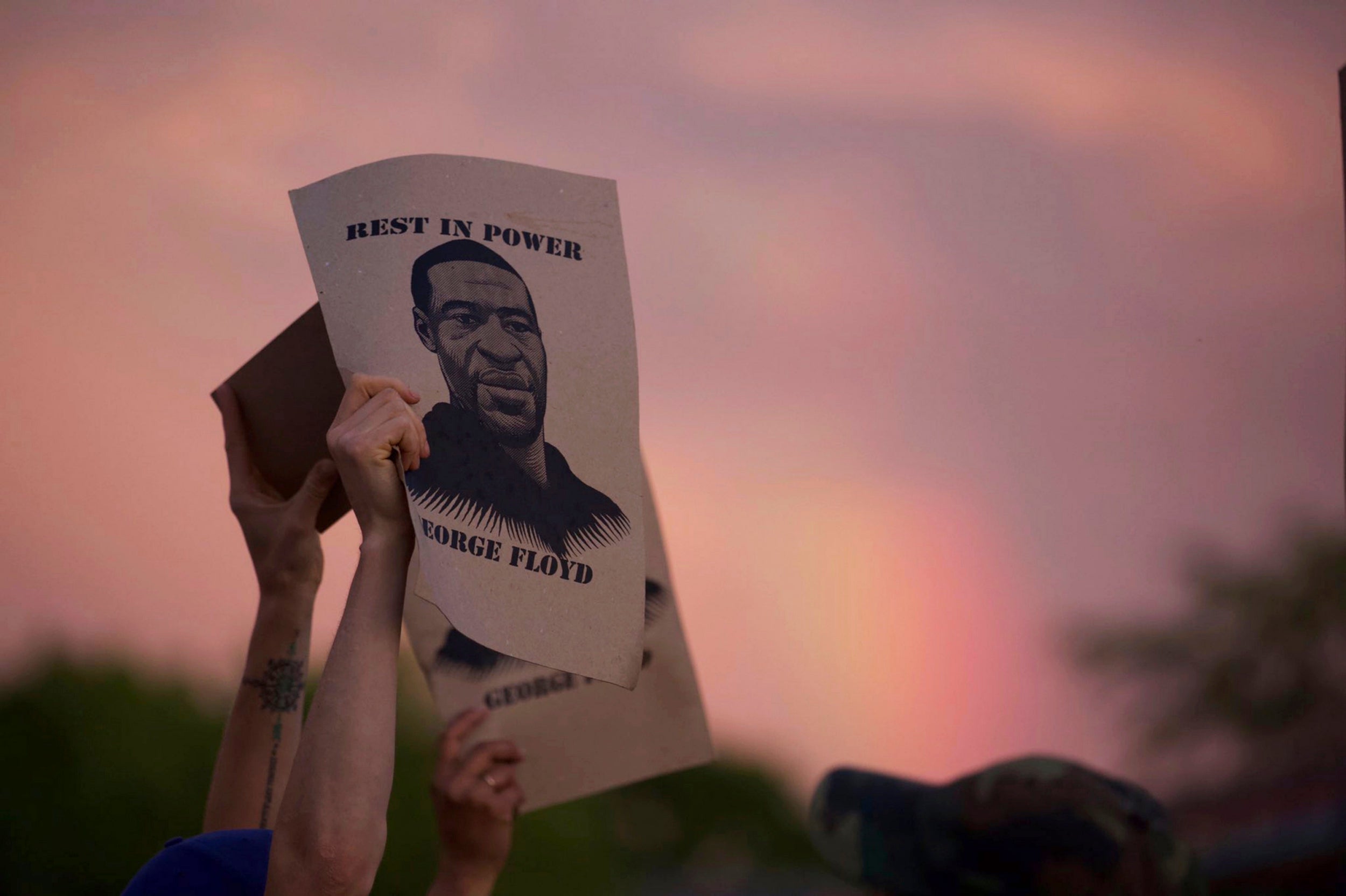 A protester holds a sign with an image of George Floyd