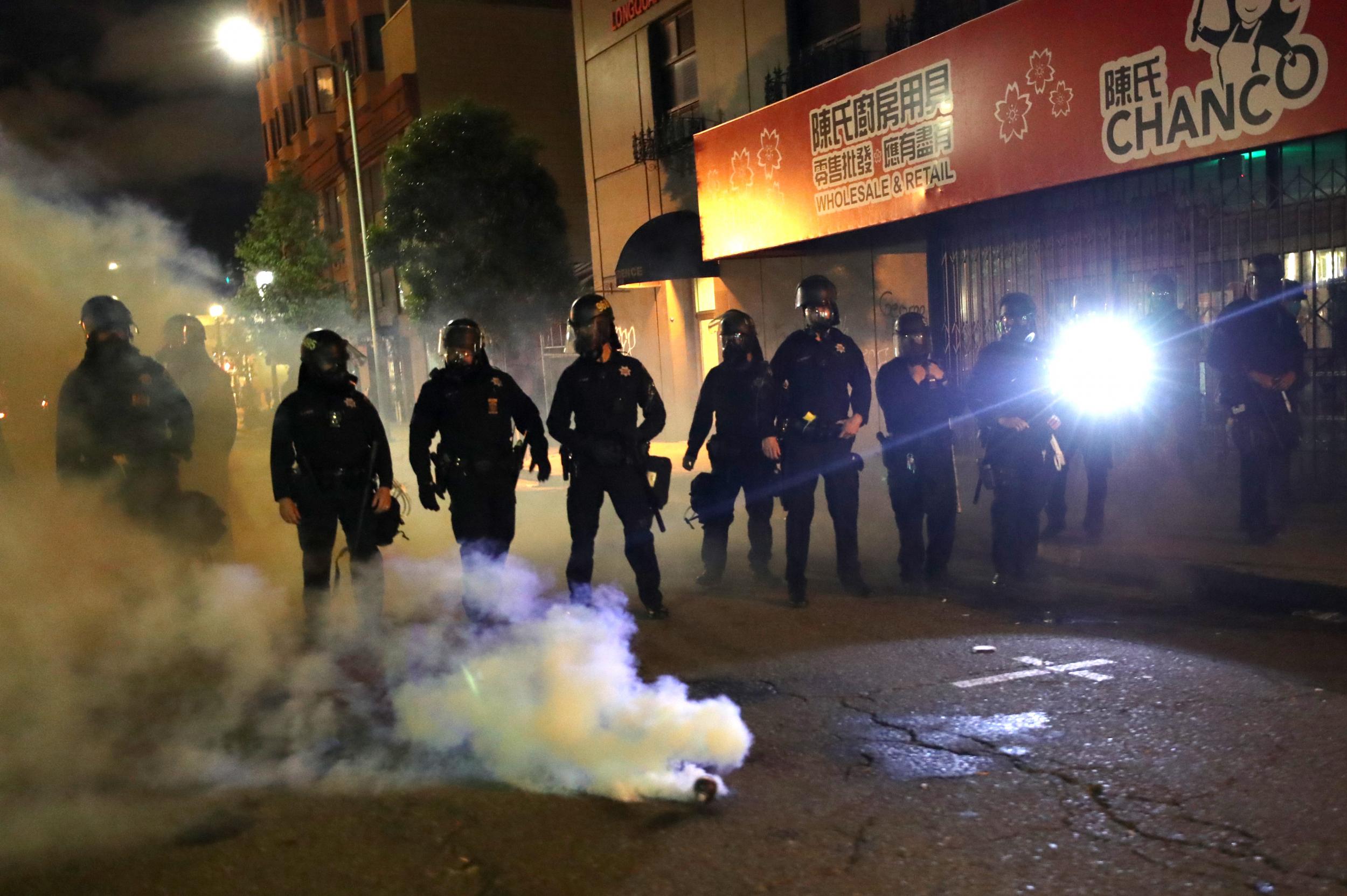 Police officers stand behind a canister of tear gas during a protest in Oakland, California on 29 May.