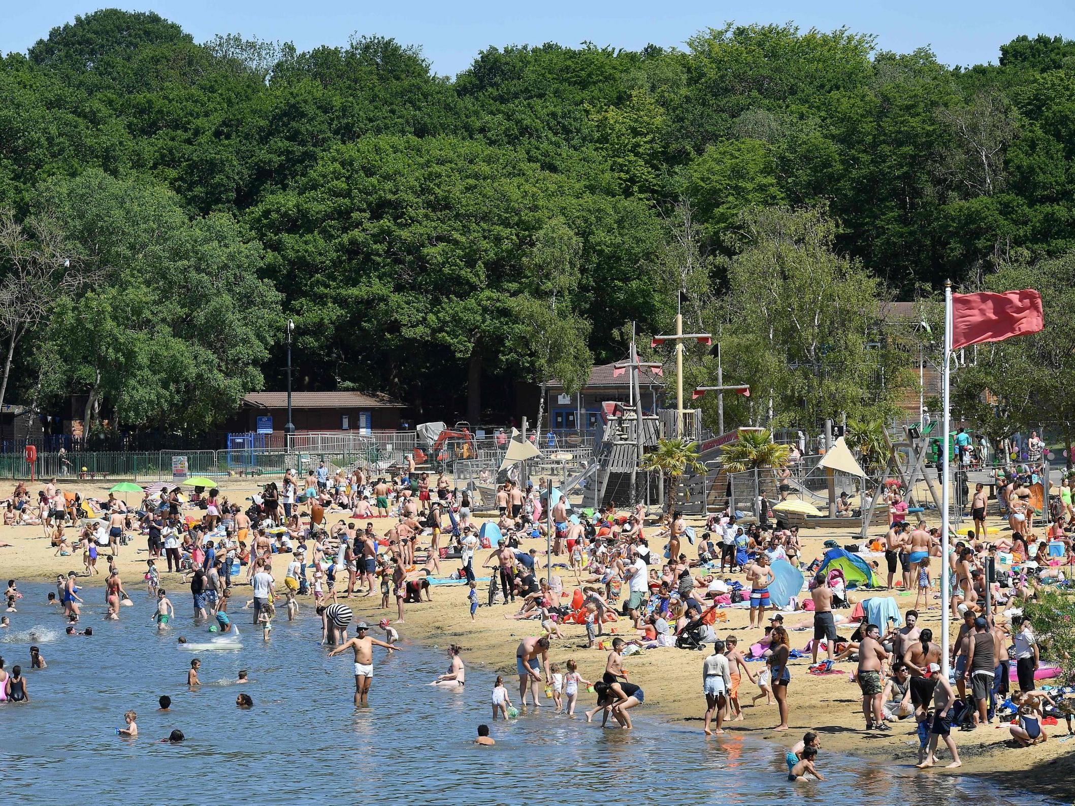 People enjoy the sunshine in the water and on the beach at Ruislip Lido in west London on Saturday