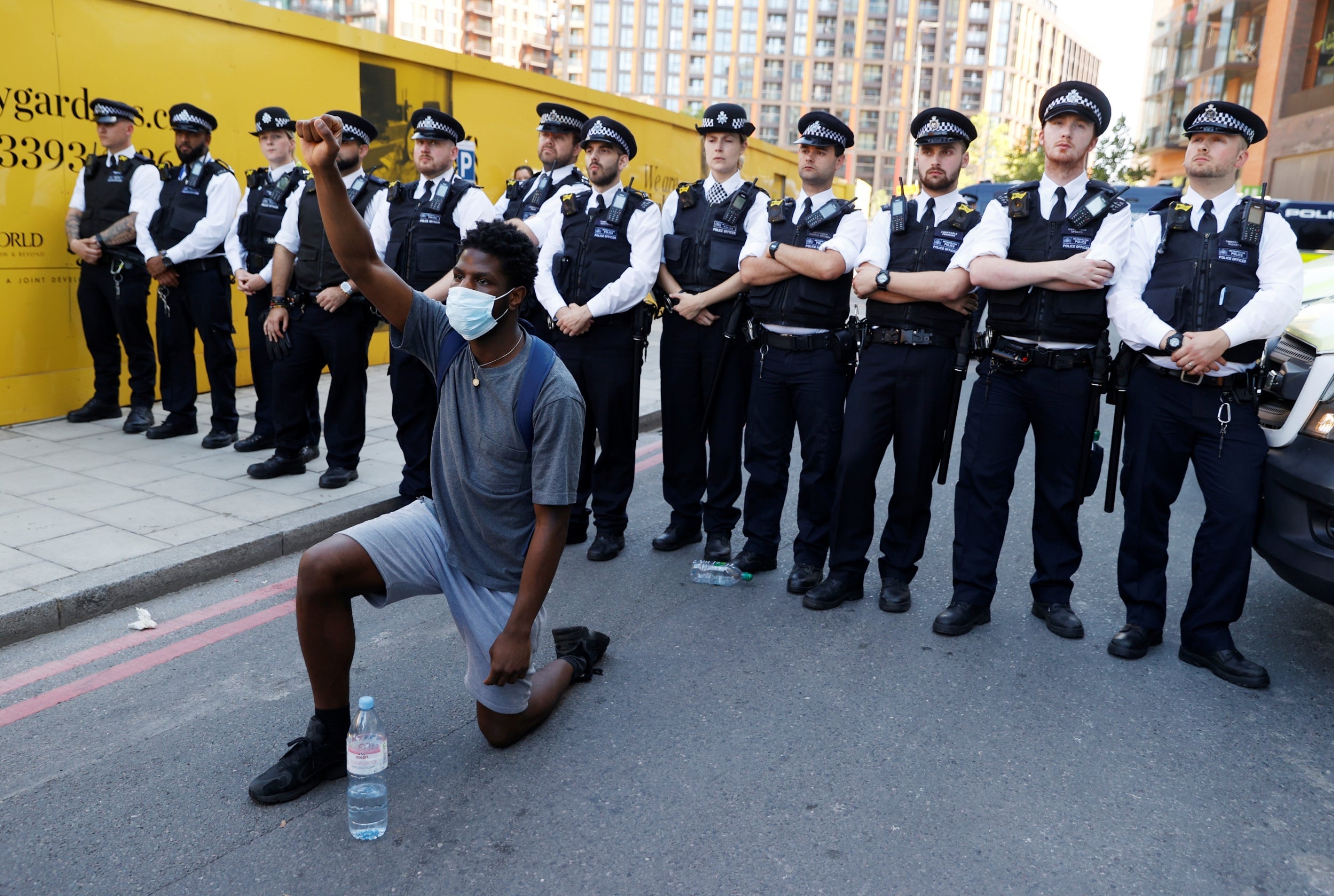 A man wearing a protective face mask kneels in front of police officers during a protest against George Floyd’s death near the US embassy (Reuters)