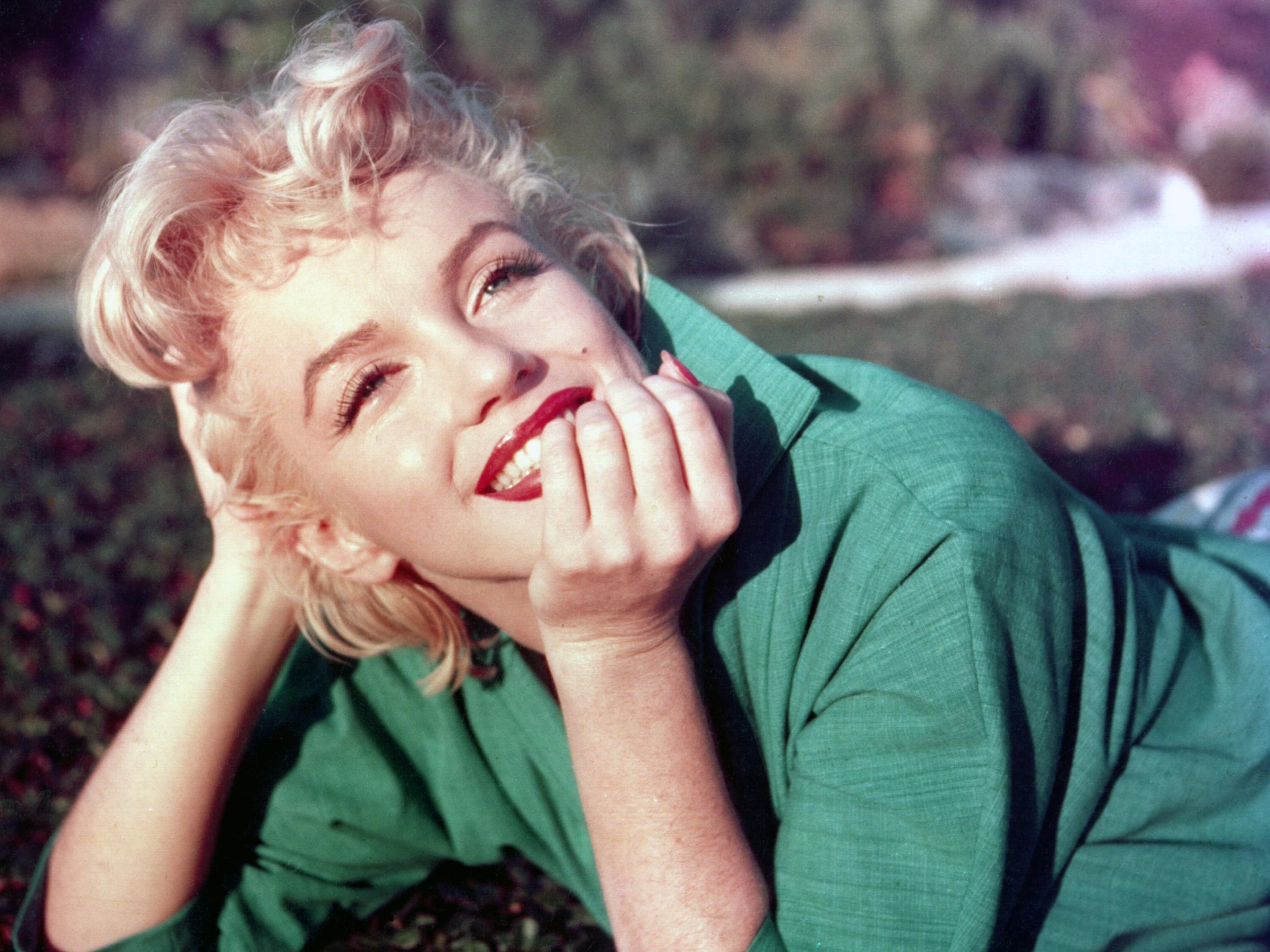 Marilyn Monroe poses for a portrait laying on the grass in 1954 in Palm Springs, California