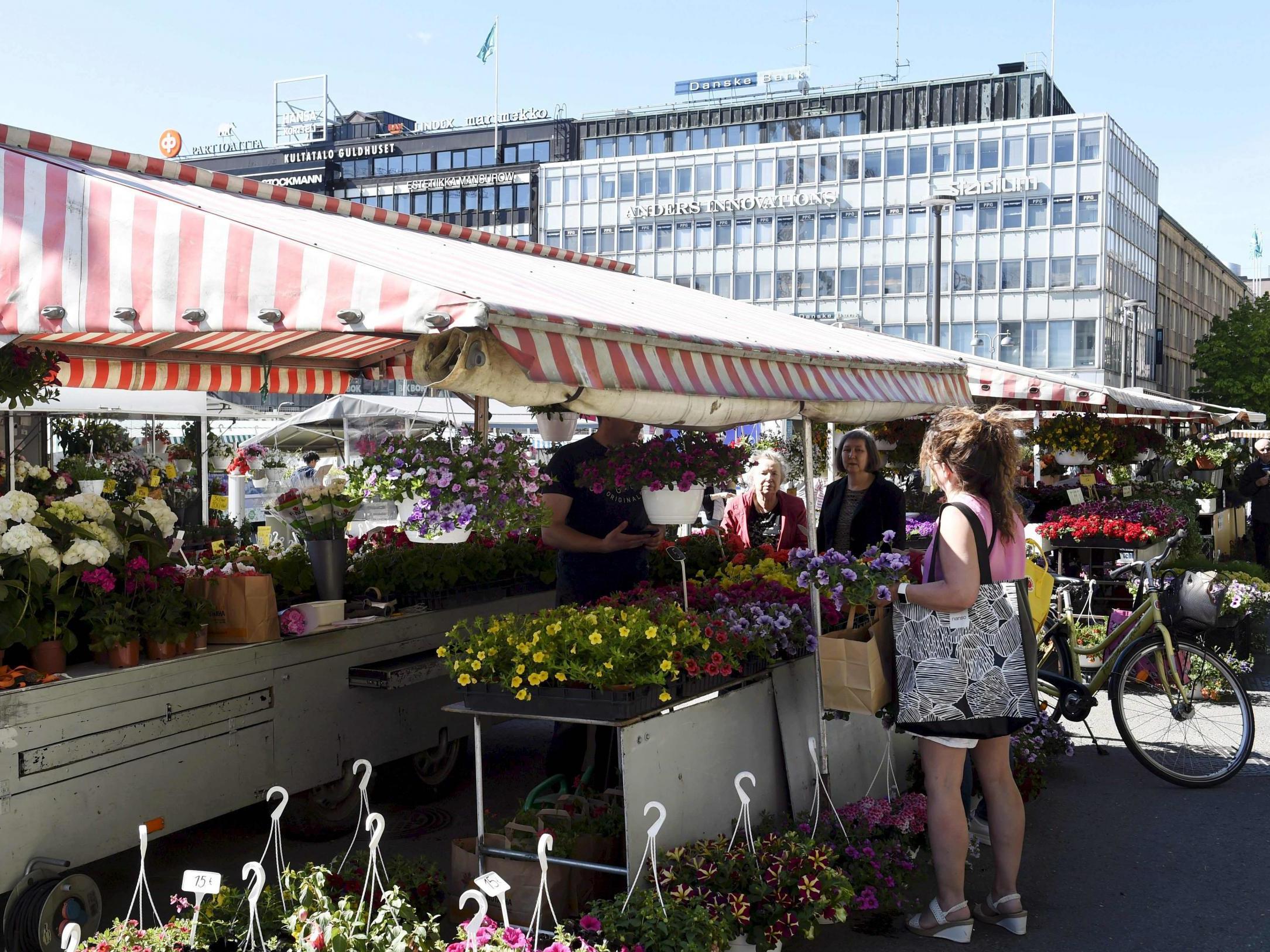 A woman buys flowers at the market square in Turku, Finland, 28 May